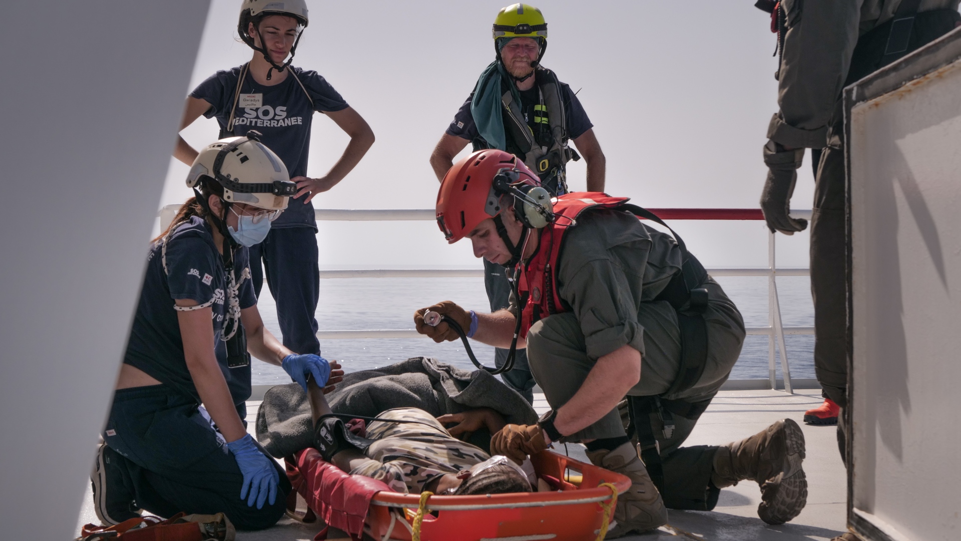 SOS Mediterranee and IFRC crewmembers prepare a pregnant woman who was rescued from the Central Mediterranean to be airlifted away for medical treatment in August 2023.