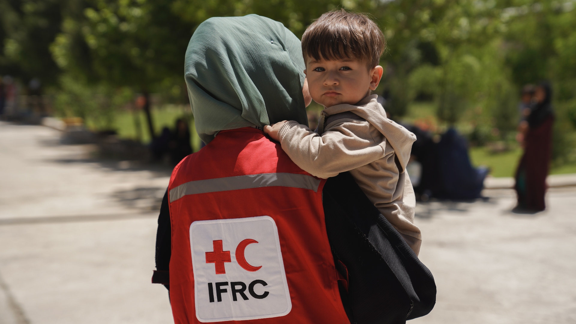Una trabajadora de la IFRC en Afganistán sostiene en brazos a un niño cuya familia está recibiendo asistencia en efectivo para ayudarles a hacer frente a las múltiples crisis en el país en agosto de 2023.