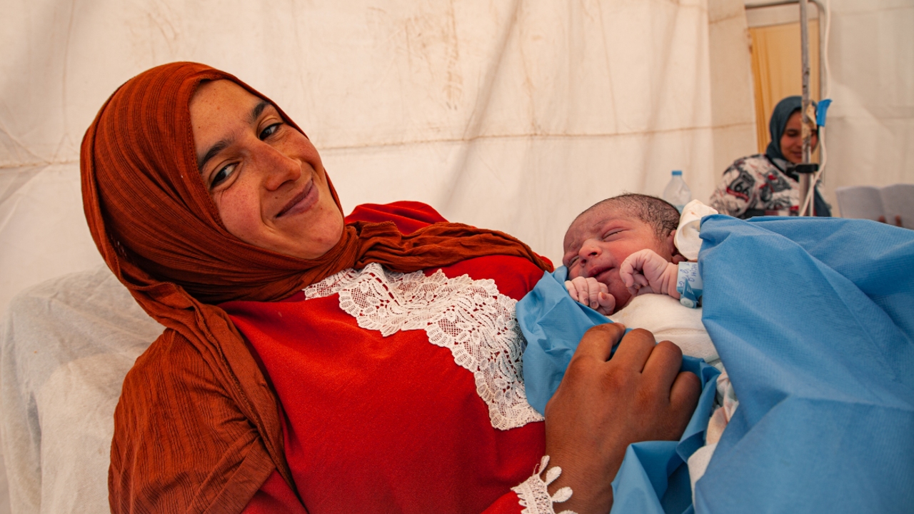 Nezha from Amizmiz, Morocco cradles her newborn son, Anas, in her arms in a makeshift tented maternity ward following the September 8 earthquake.