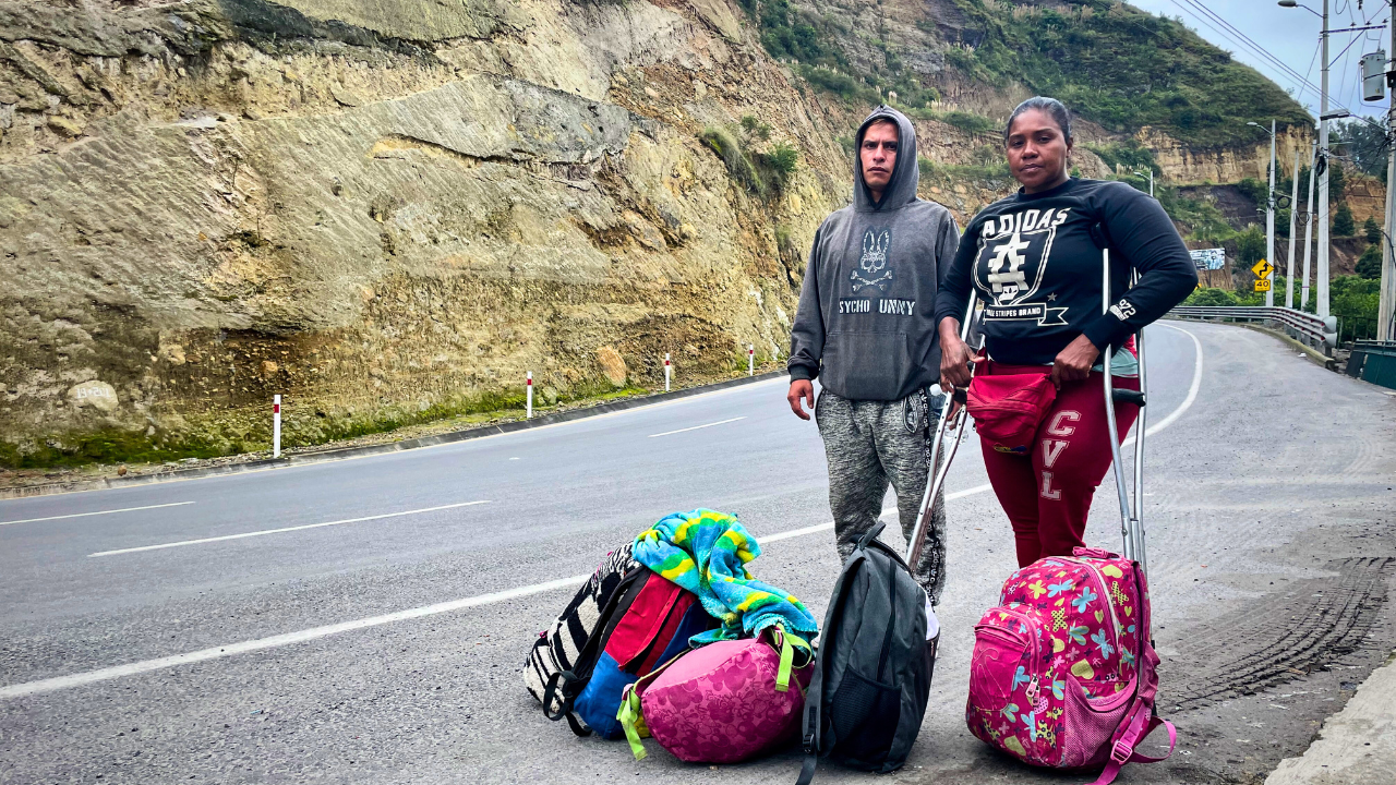  Cristia y Winston están al lado de una carretera. Son una pareja que migró desde Venezuela, han recorrido miles de kilómetros primero a través de Colombia, camino al sur, hacia Ecuador.