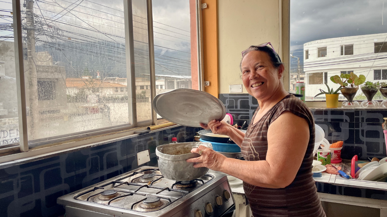 Belkis Colmenares sonríe a la cámara desde su cocina. Ella fue una de las personas migrantes que recibió ayuda en efectivo de la Cruz Roja Ecuatoriana para cubrir necesidades básicas como alimentos, alquiler y medicinas.  