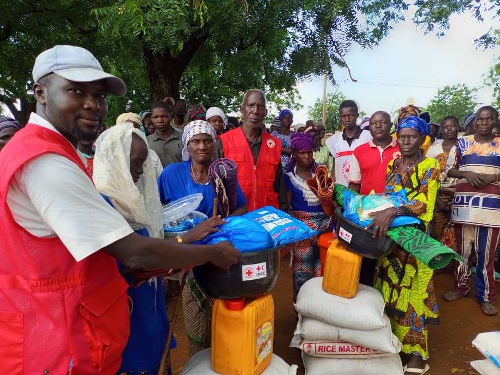 Personas desplazadas por la violencia en Burkina Faso se reúnen en un punto de distribución establecido por la Cruz Roja de Benín.