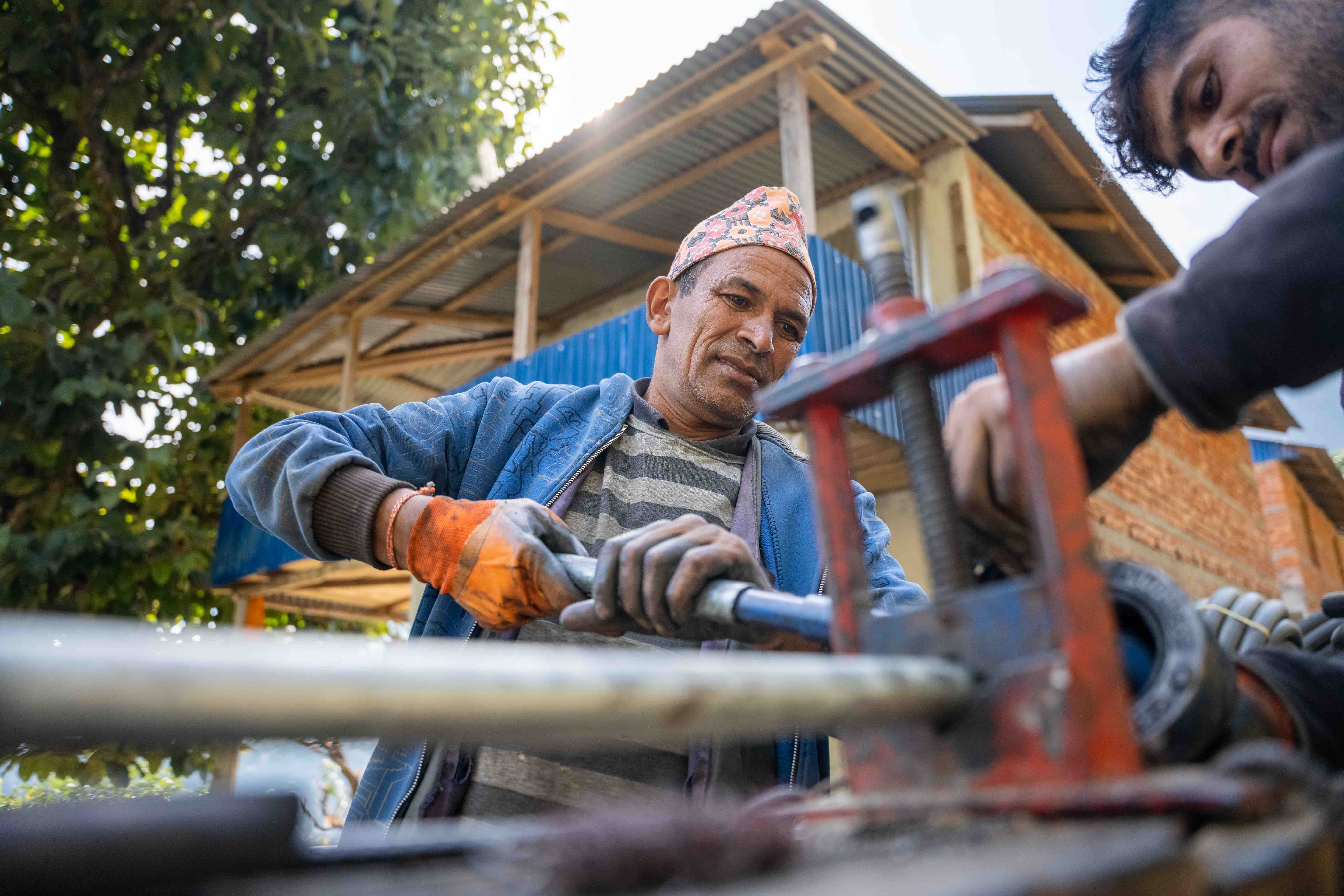 Two members of the local community install pipes as part of the final installation of a new well, water collection basin and distribution point in their remote, rural Nepali village.