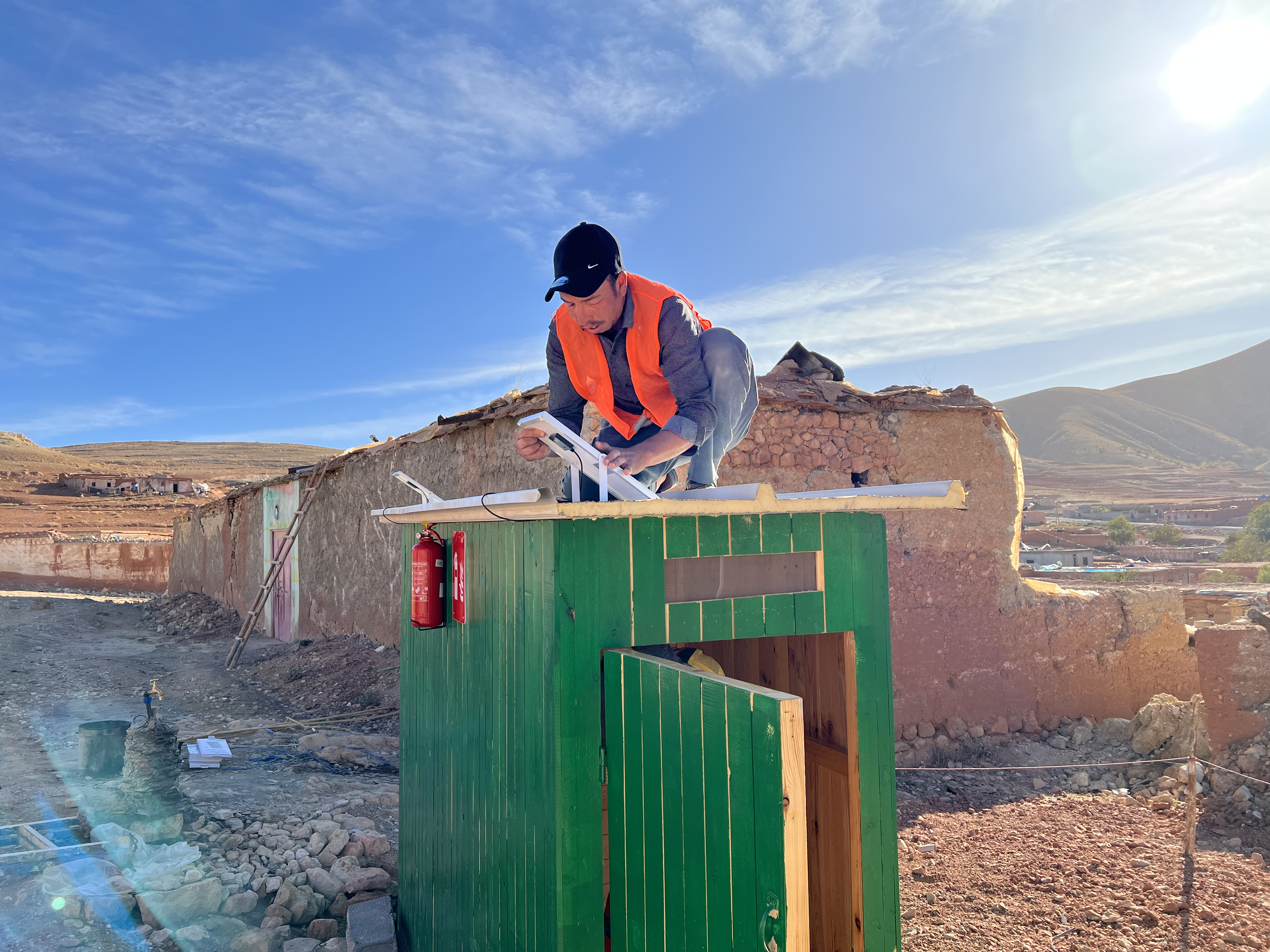 A volunteer with the Moroccan Red Crescent puts the finishing touches on a shower stall for a community that lost nearly all its access to clean water following the September 2023 Earthquake.
