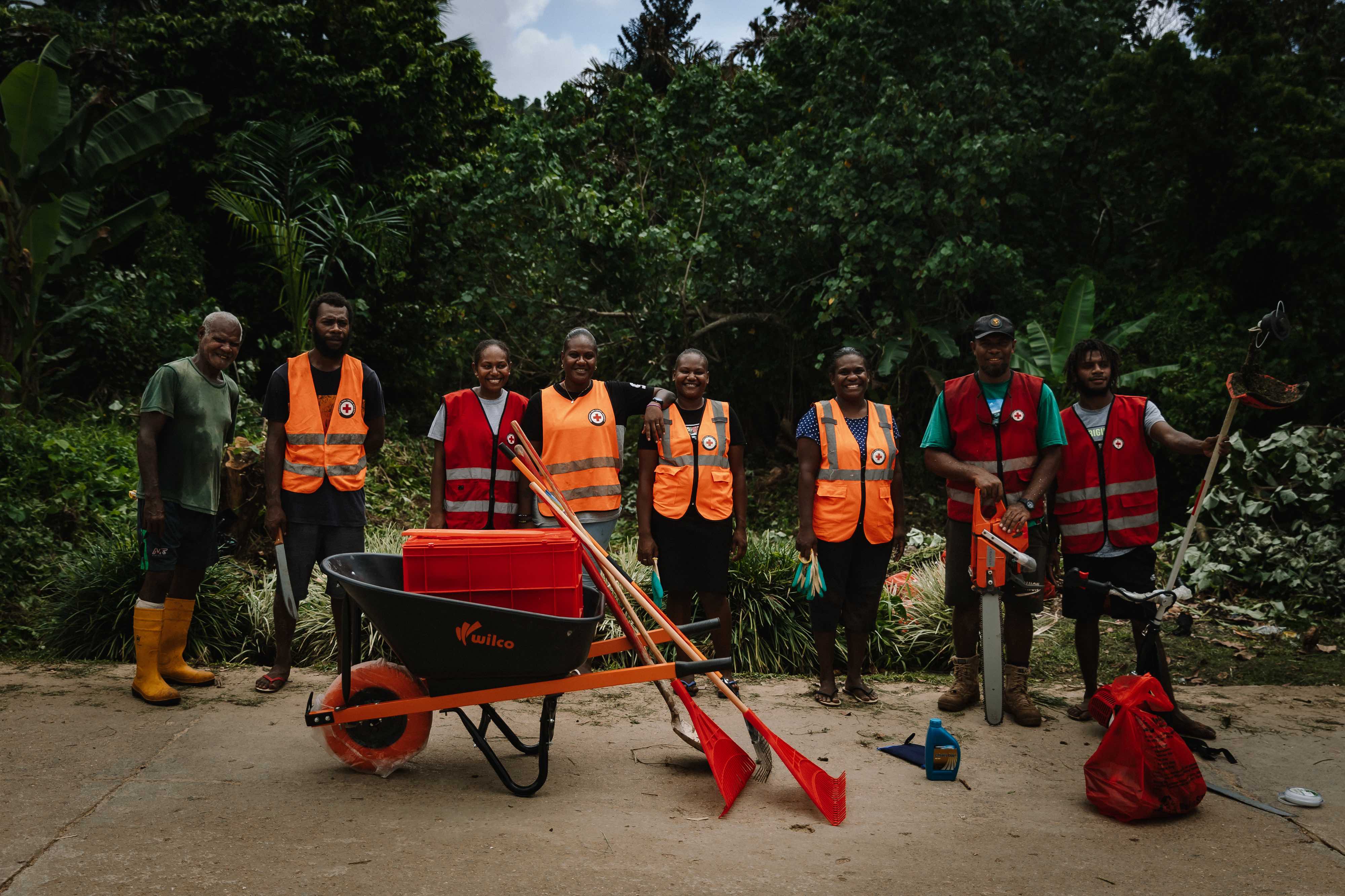 Members of the clean up crew stand behind the wheelbarrow, rakes, shovels and other tools they bought in order to clear vegetation and garbage from the river that runs near their town.