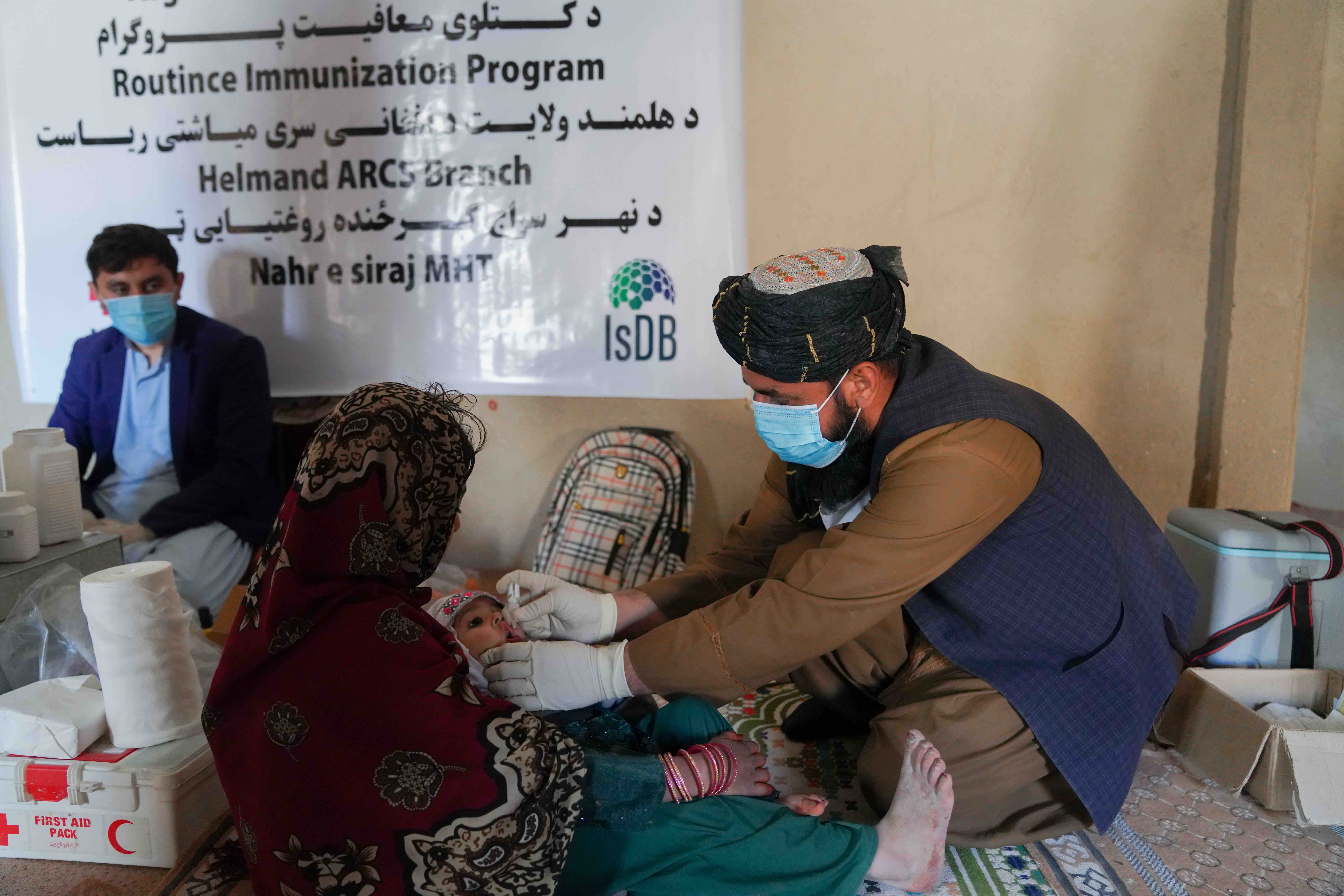 An Afghan Red Crescent mobile team member provides immunization for an infant during an immunization drive in July 2023. 