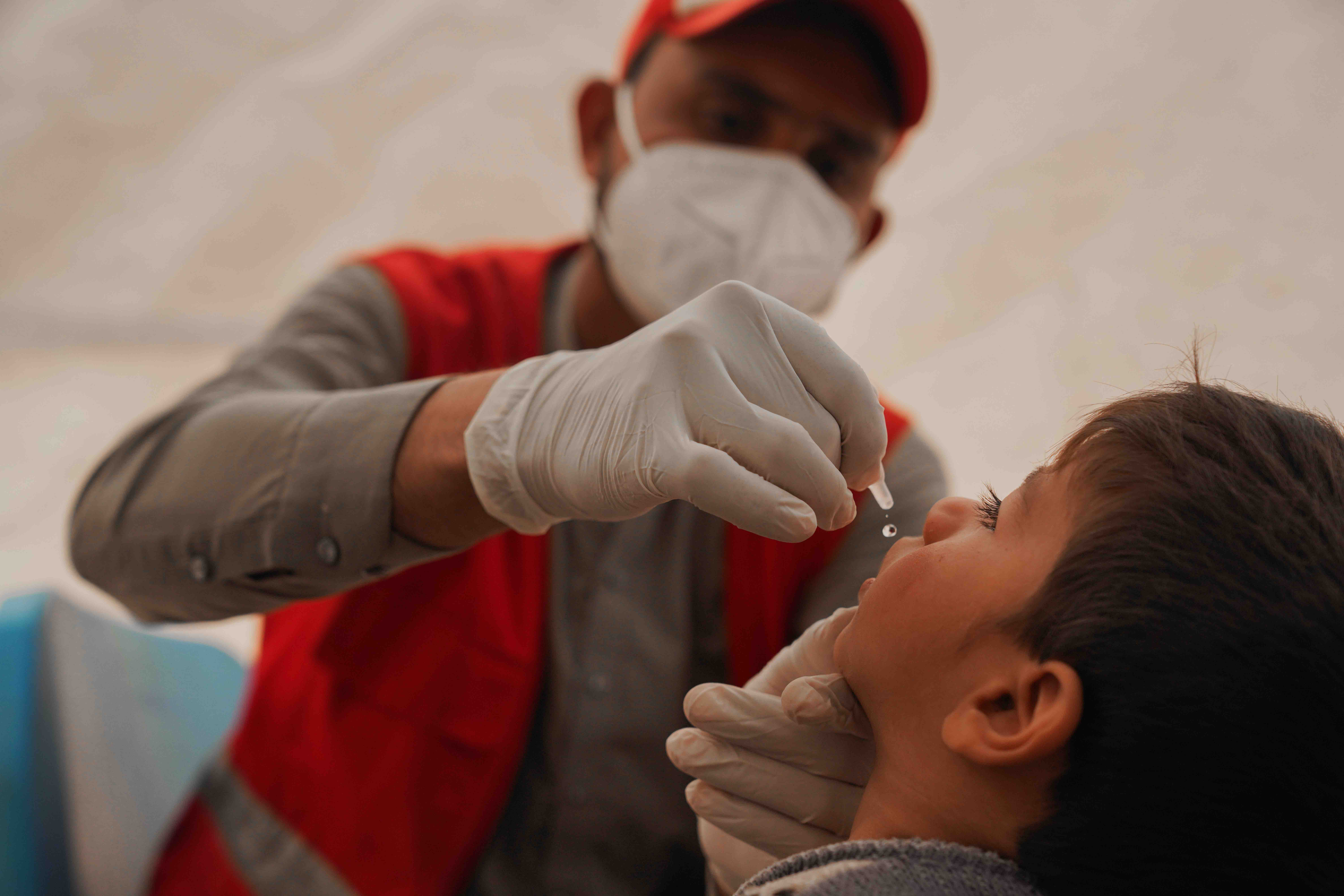 Small children are particularly vulnerable to many infectious diseases. Here an Afghan Red Crescent mobile health team member gives oral polio vaccine to a small child in Helmand province.