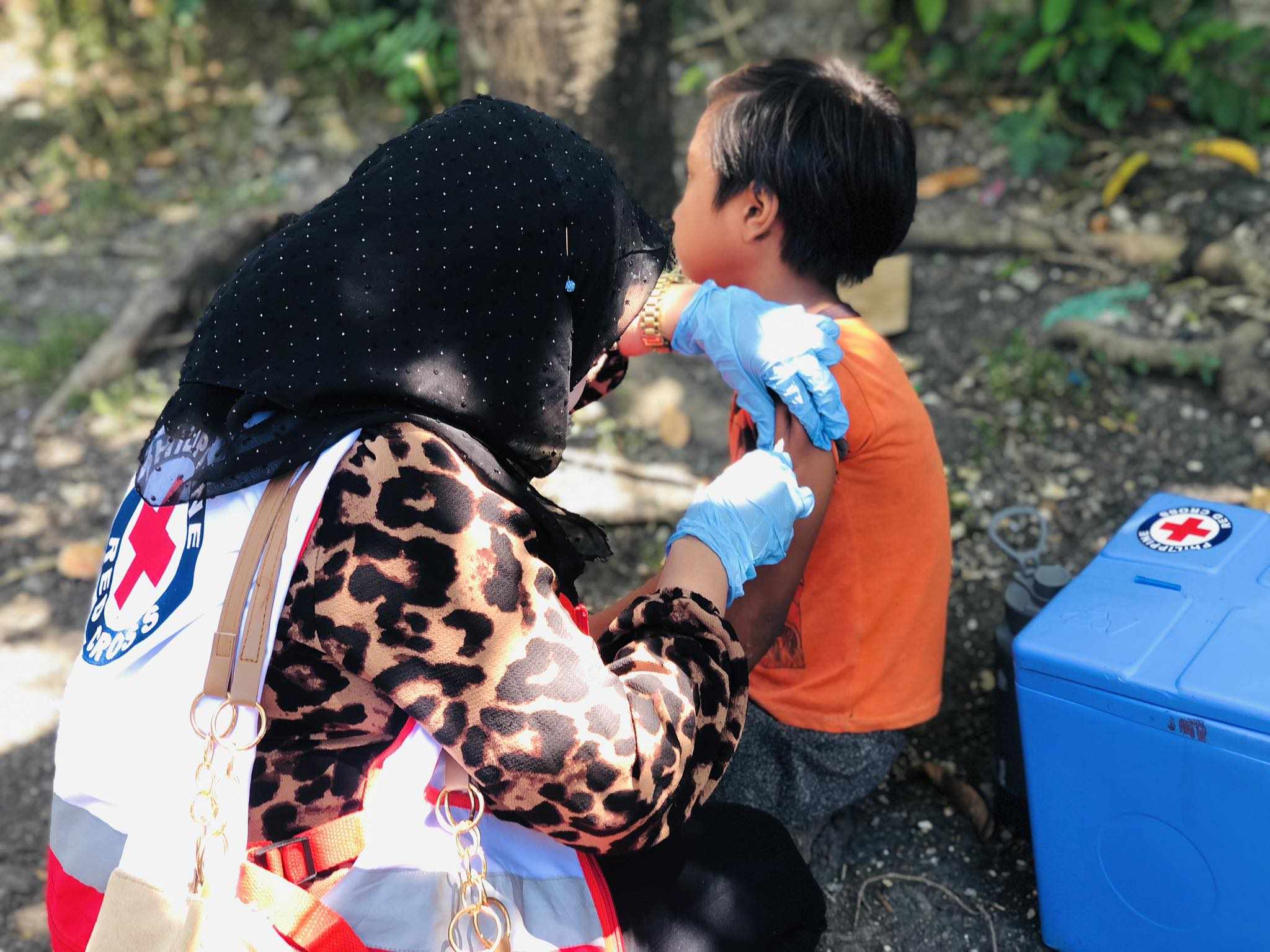 A volunteer from the Philippine Red Cross delivers a vaccination against measles to a young boy in Cotabato, Philippines in April 2024.