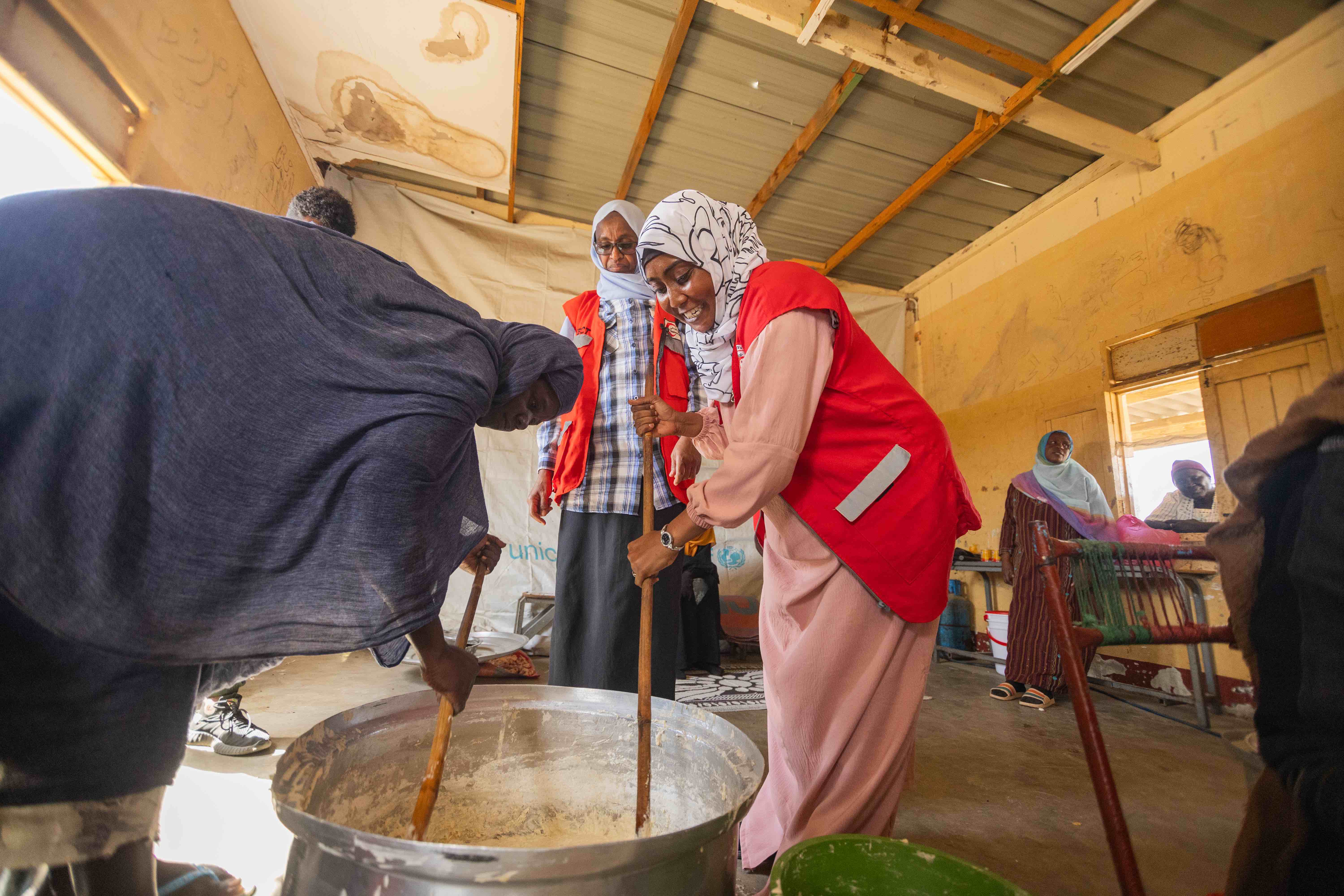 SRCS volunteer nurse Wajdan Hassan Ahmed, together with other volunteers and displaced families prepare a meal at a camp for displaced persons, Port Sudan, Sudan.