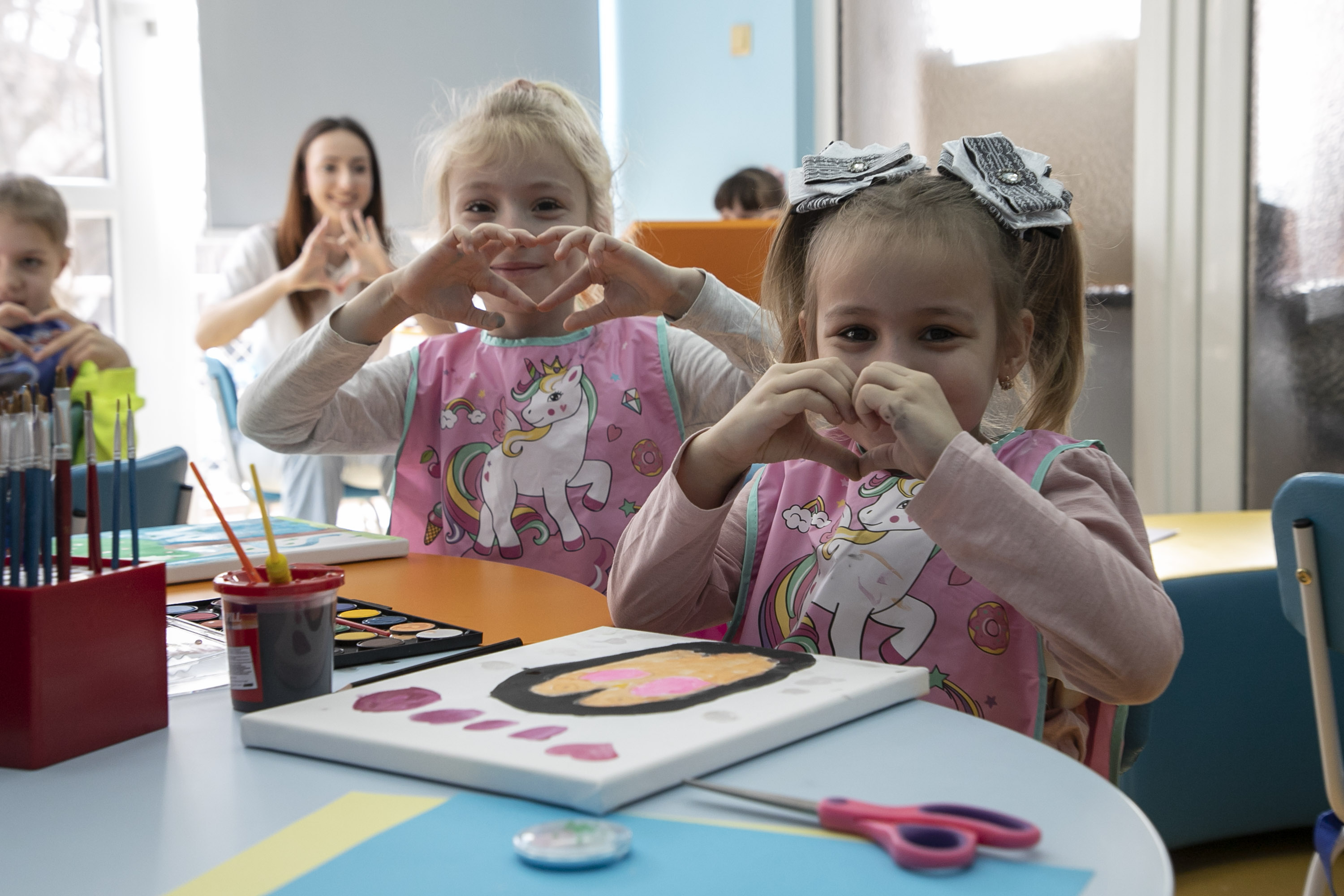 Des enfants font le signe du cœur avec leurs mains lors d'une séance d'art-thérapie à l'antenne de la Croix-Rouge bulgare à Plovdiv, dans le cadre du projet UE pour la santé. 