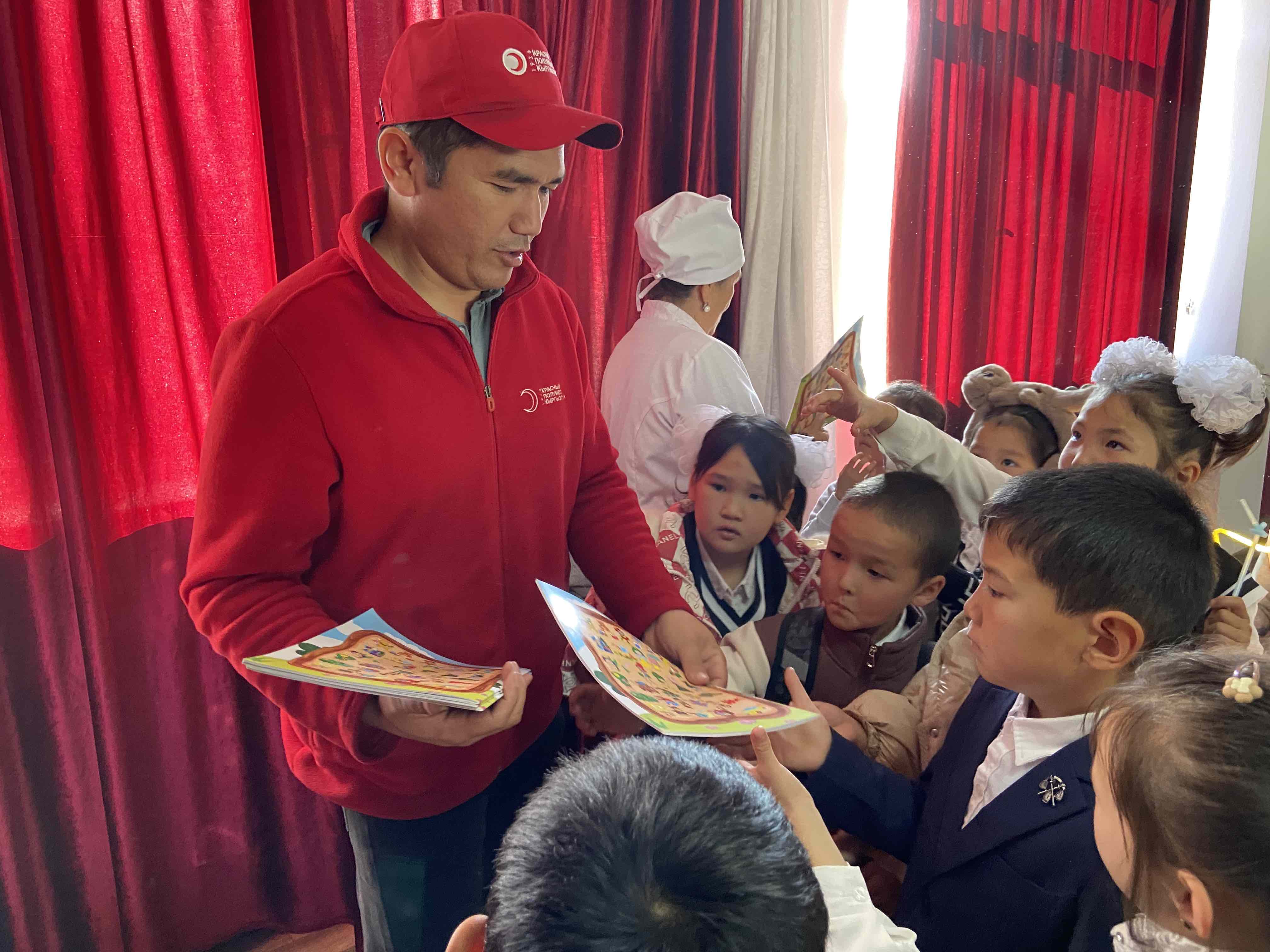 A Kyrgyzstan Red Crescent volunteer hands out comic books to children who have been vaccinated against measles.