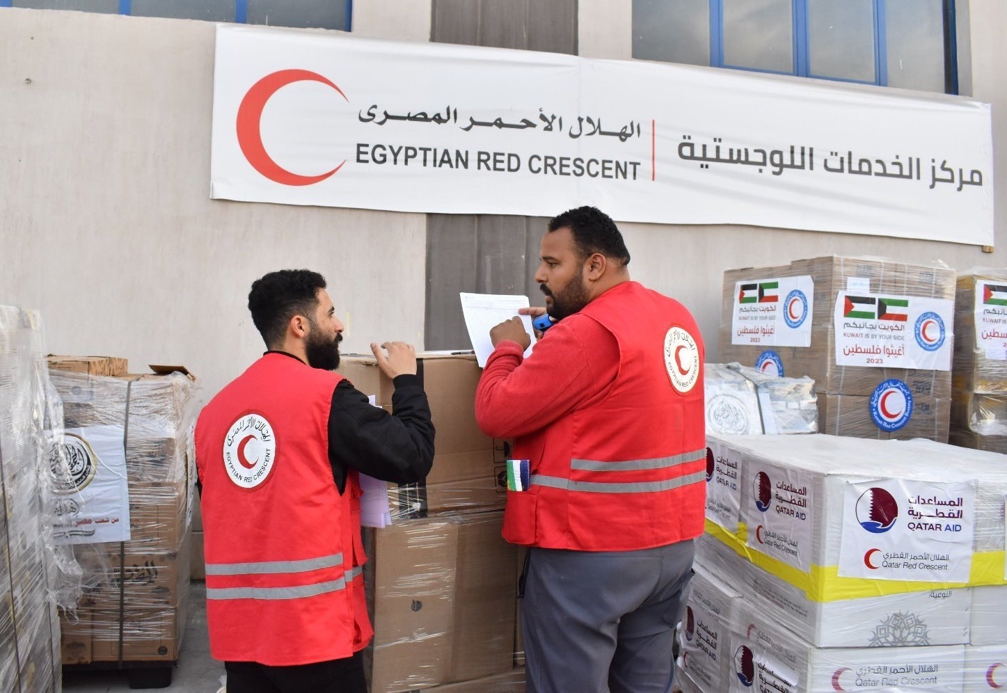 Two members of the Egyptian Red Crescent operations team assess the inventory of aid that will be delivered into Gaza. Since the escalation of hostilities between Israel and Palestine in October 2023, the Egyptian Red Crescent has delivered nearly 18,000 truck loads of medical supplies, food, and other goods into Gaza.