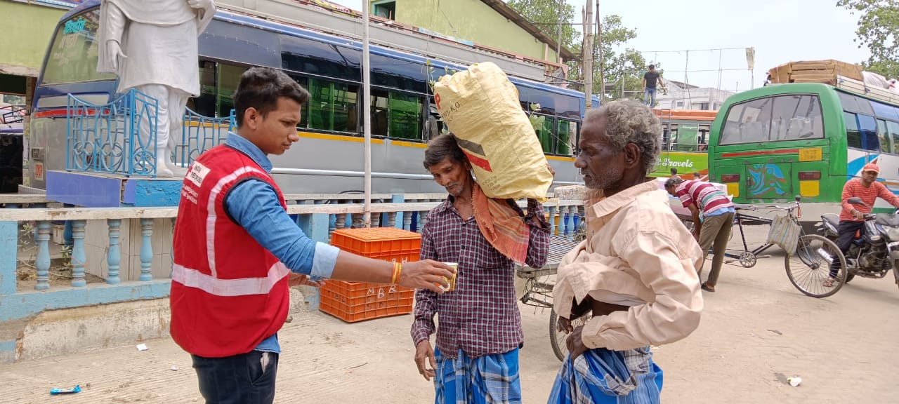 A volunteer from the Indian Red Cross hands out water to two people during a heatwave.