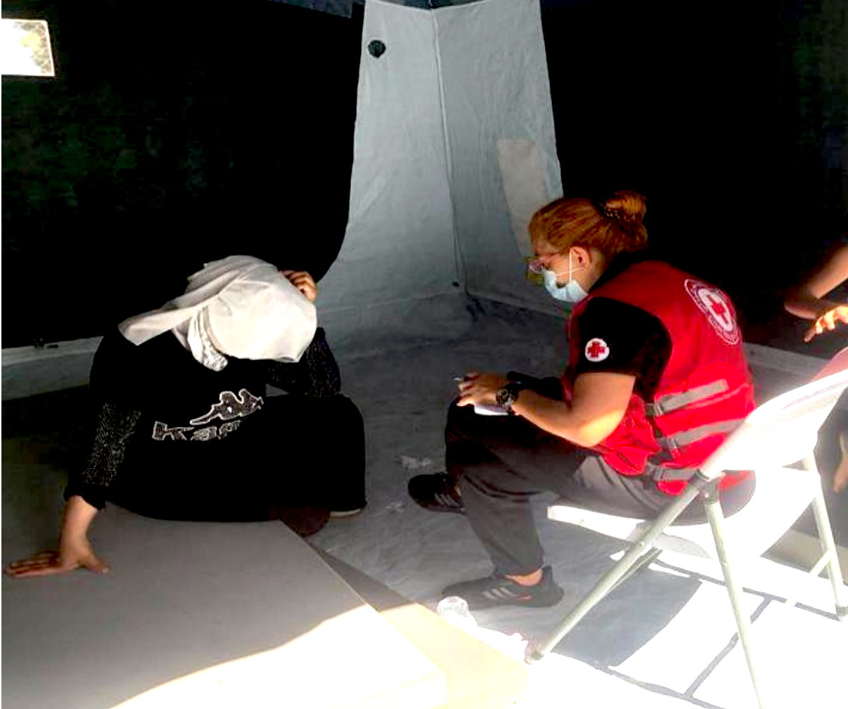 A member of the Lebanese Red Cross Humanitarian Service Point team that responds to shipwrecked migrants speaks with a woman who recently arrived on Lebanese shores.