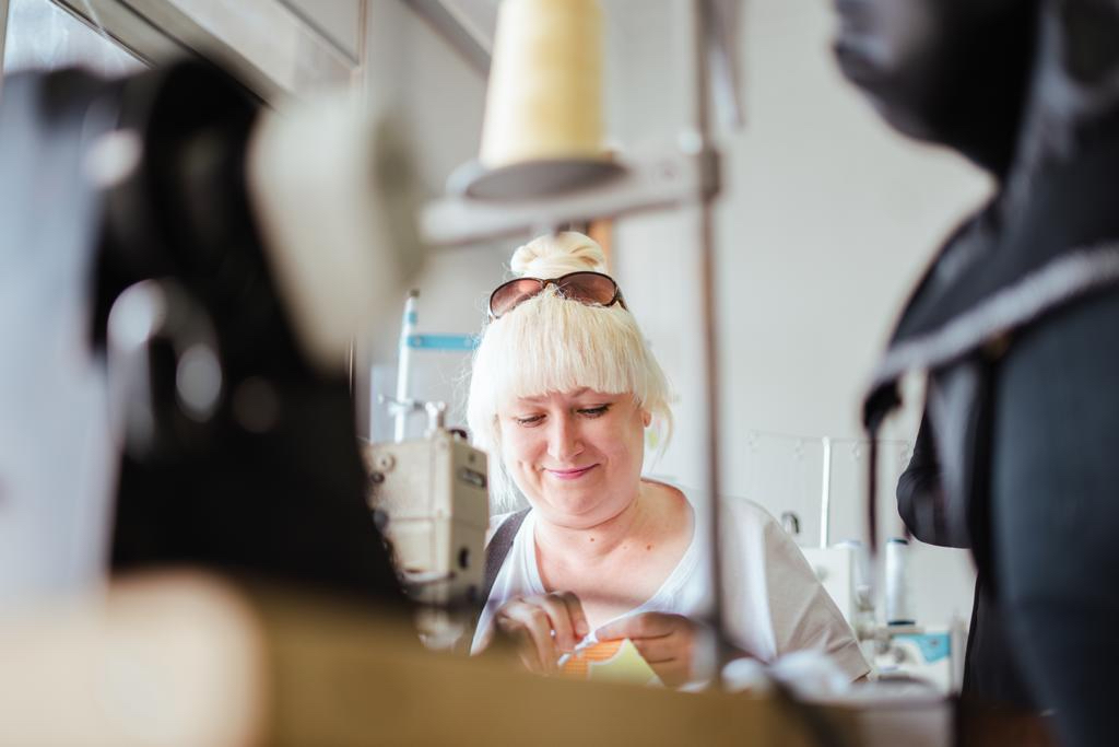 Surrounded by sewing machines, a woman from Ukraine uses needle and thread to finish a project during an art therapy programme organized by the Portuguese Red Cross.