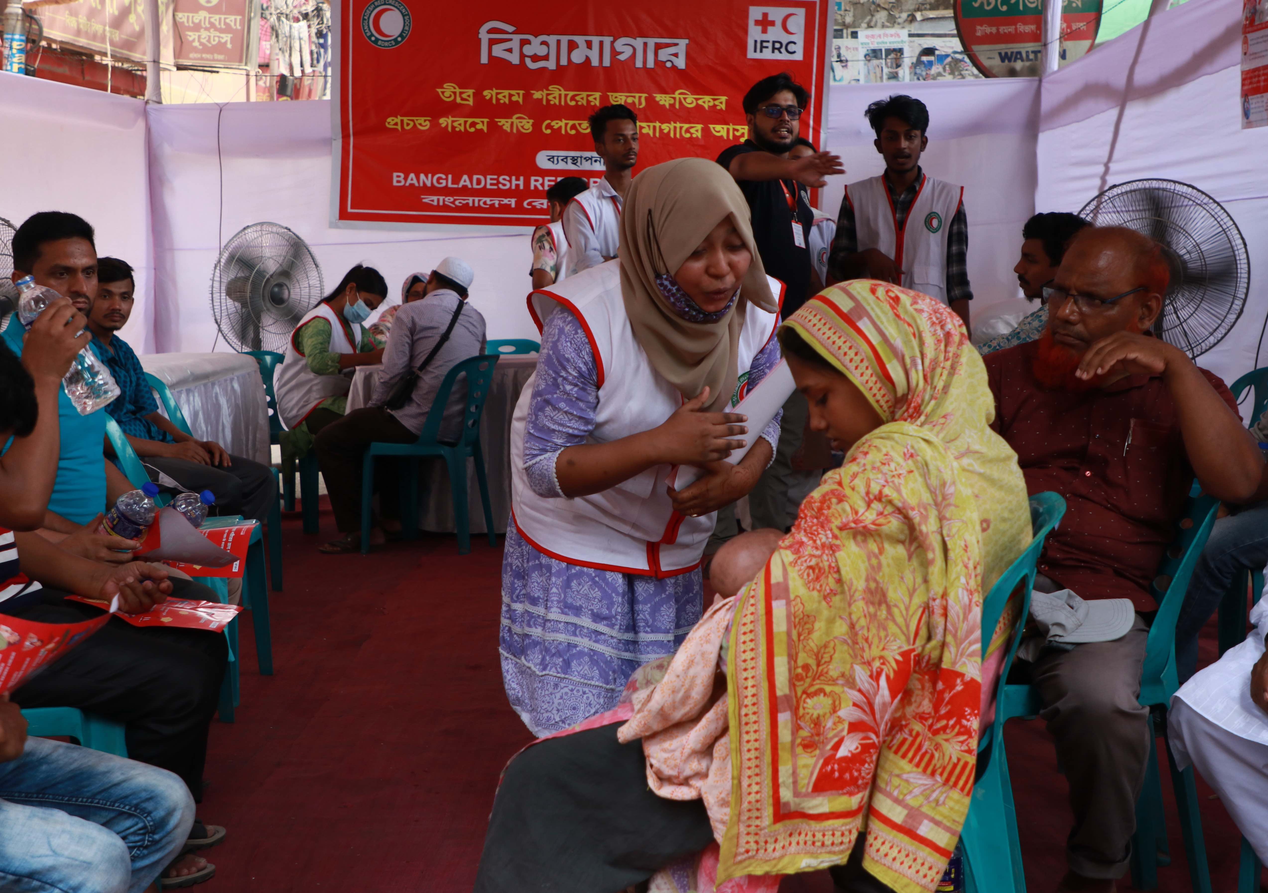 A volunteer for the Bangladesh Red Crescent checks on a woman and her baby at a cooling station set up by the Red Crescent in Dhaka, Bangladesh. Infants are particularly susceptible to extreme heat and side effects such as dehydration.
