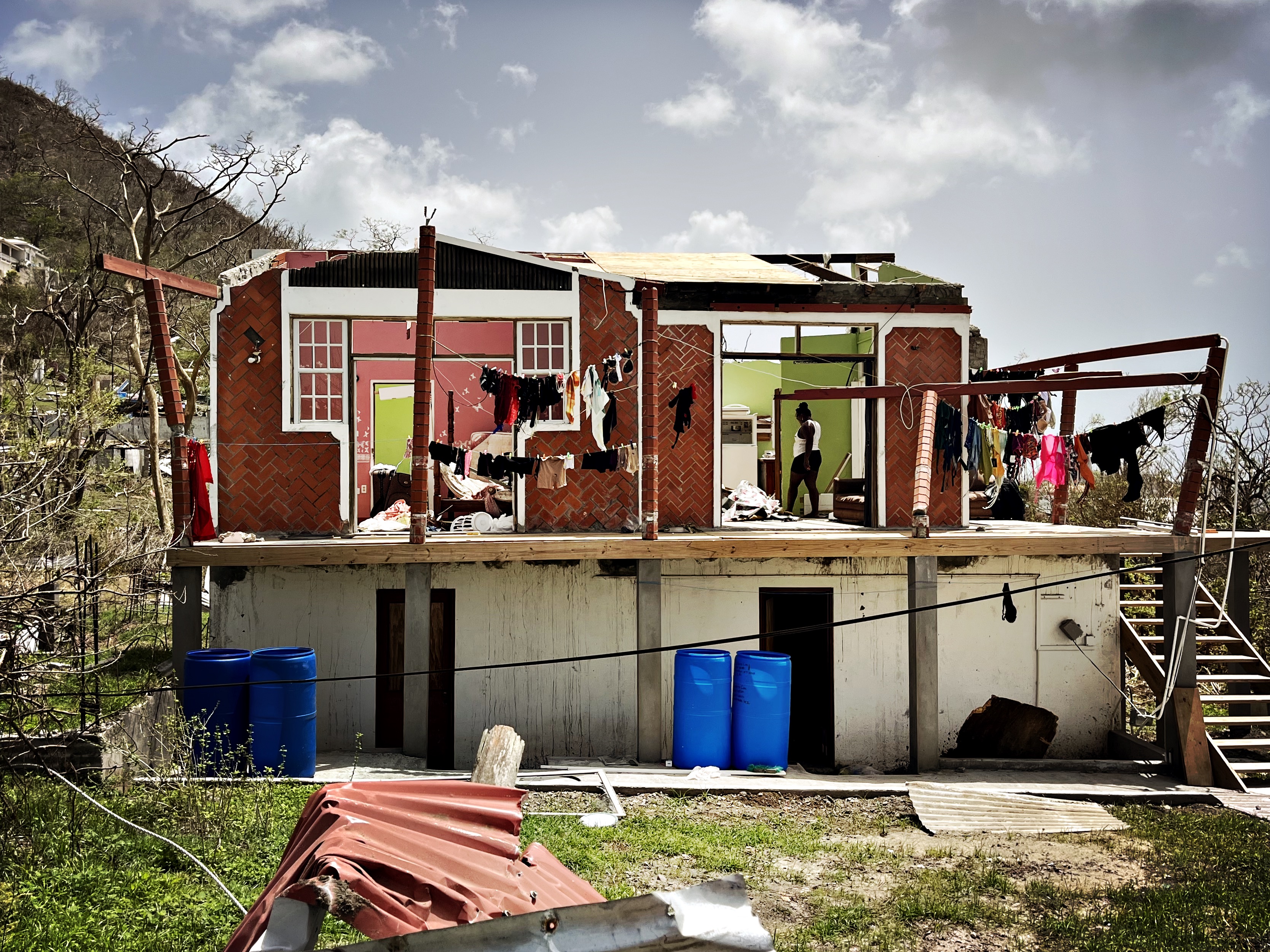 Une femme se tient dans ce qui reste de sa maison, qui a été endommagée par l'ouragan Beryl dans l'État des trois îles de la Grenade.