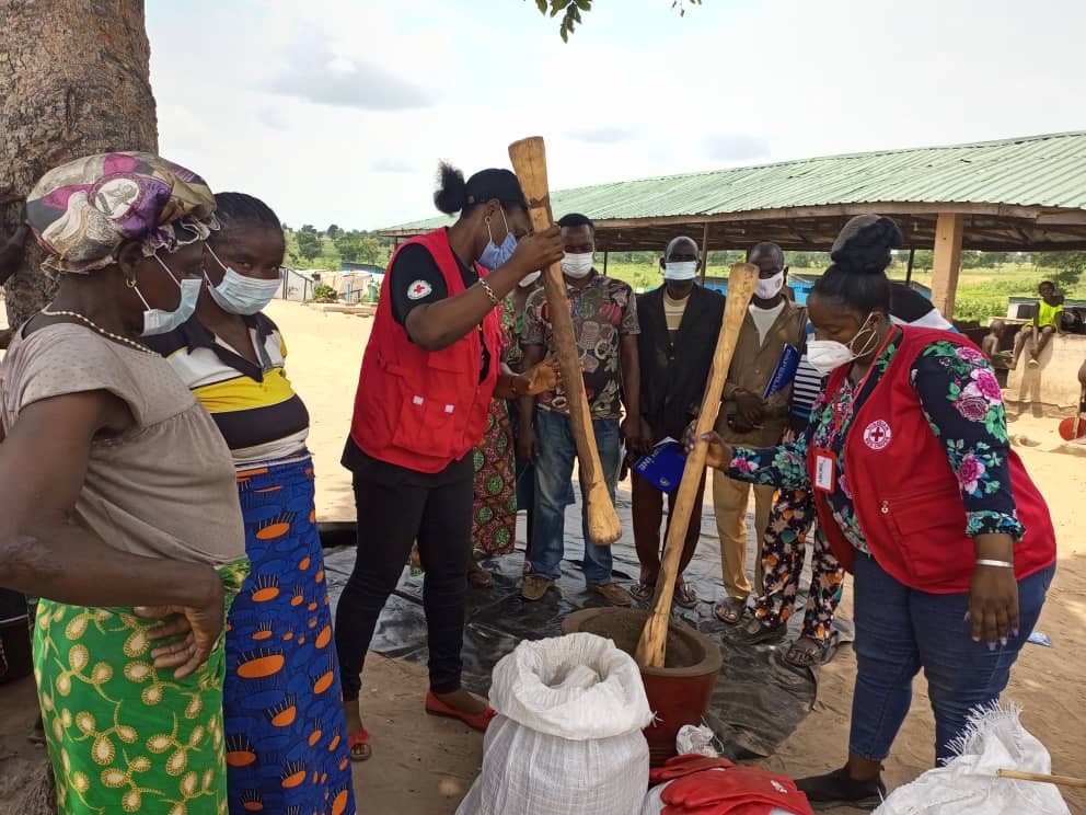 Nigerian Red Cross volunteers show people how to make fertilizers using natural ingredients such as rice husks, which they first break up by pounding them with large wooden pestles.