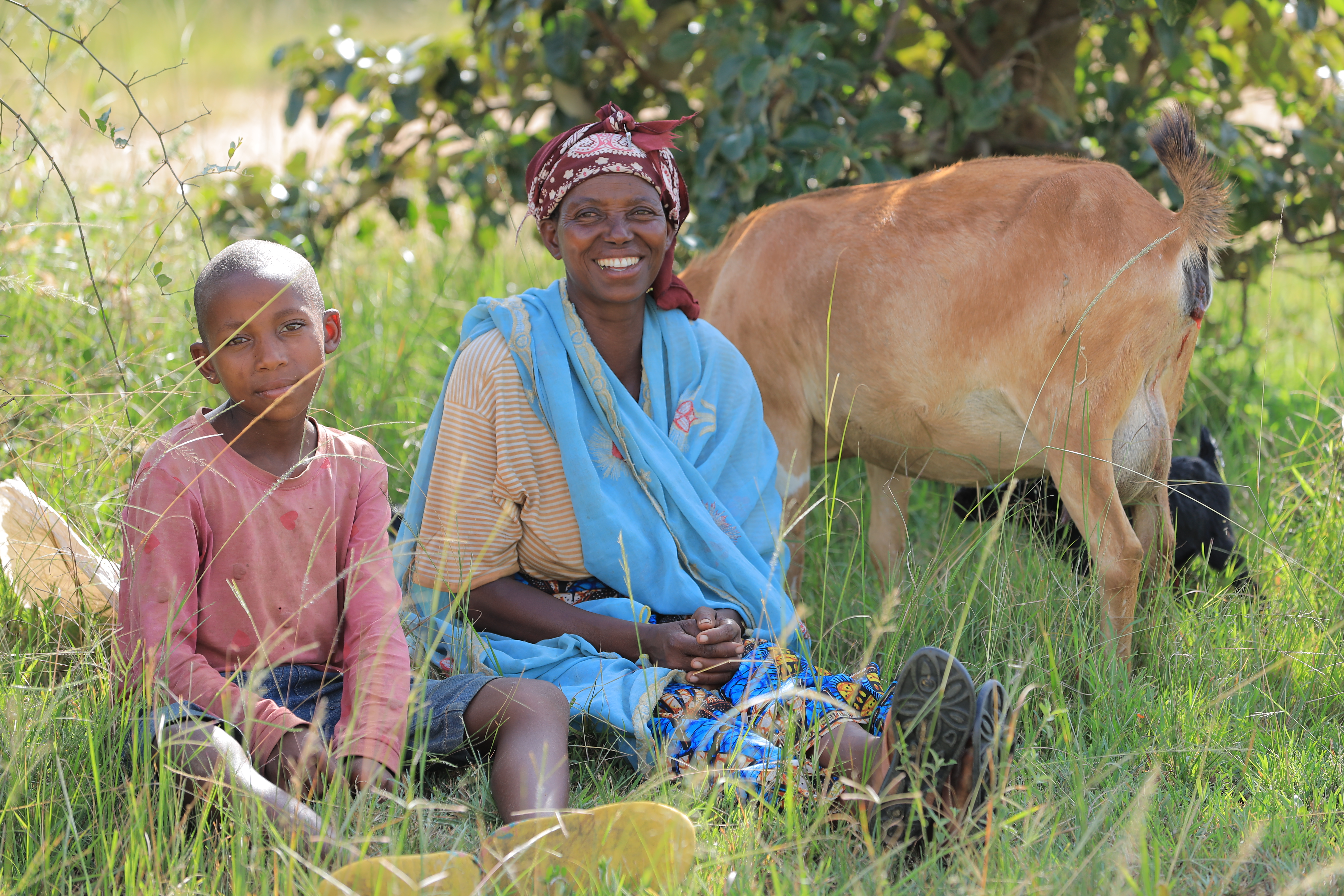 Antoinette Imanizibayo et l'un de ses enfants sont assis avec l'une des chèvres qu'elle a achetées grâce à l'argent fourni par un programme d'aide financière. 