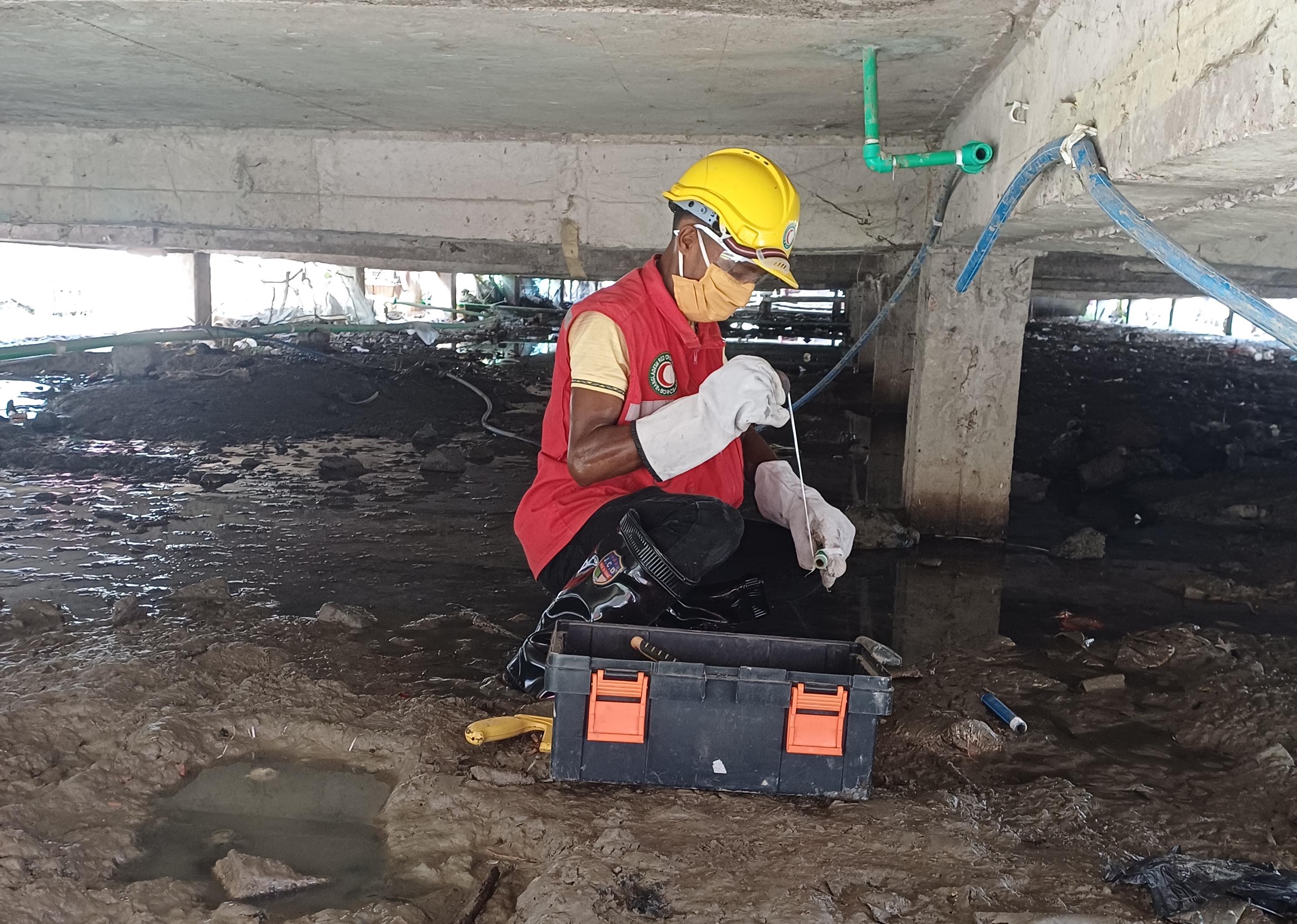 Bangladesh Red Crescent volunteer Abdul Hamid works underneath an apartment block where he is maintaining pipes that bring cooking gas that is produced from biological waste.