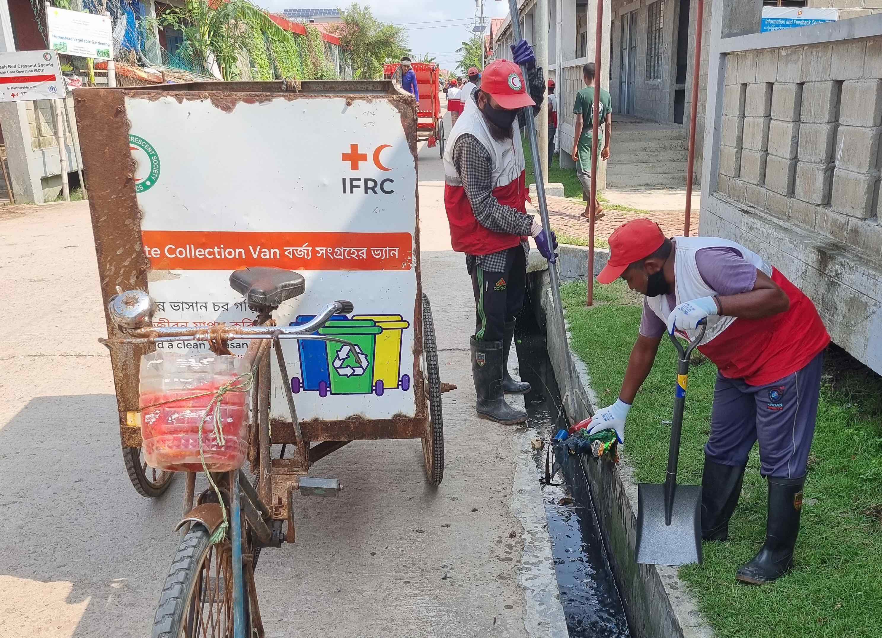 Bangladesh Red Crescent volunteer Jafor Alam and another volunteer clean a narrow concrete water canal in order to prevent blockages that can lead to flooding. 