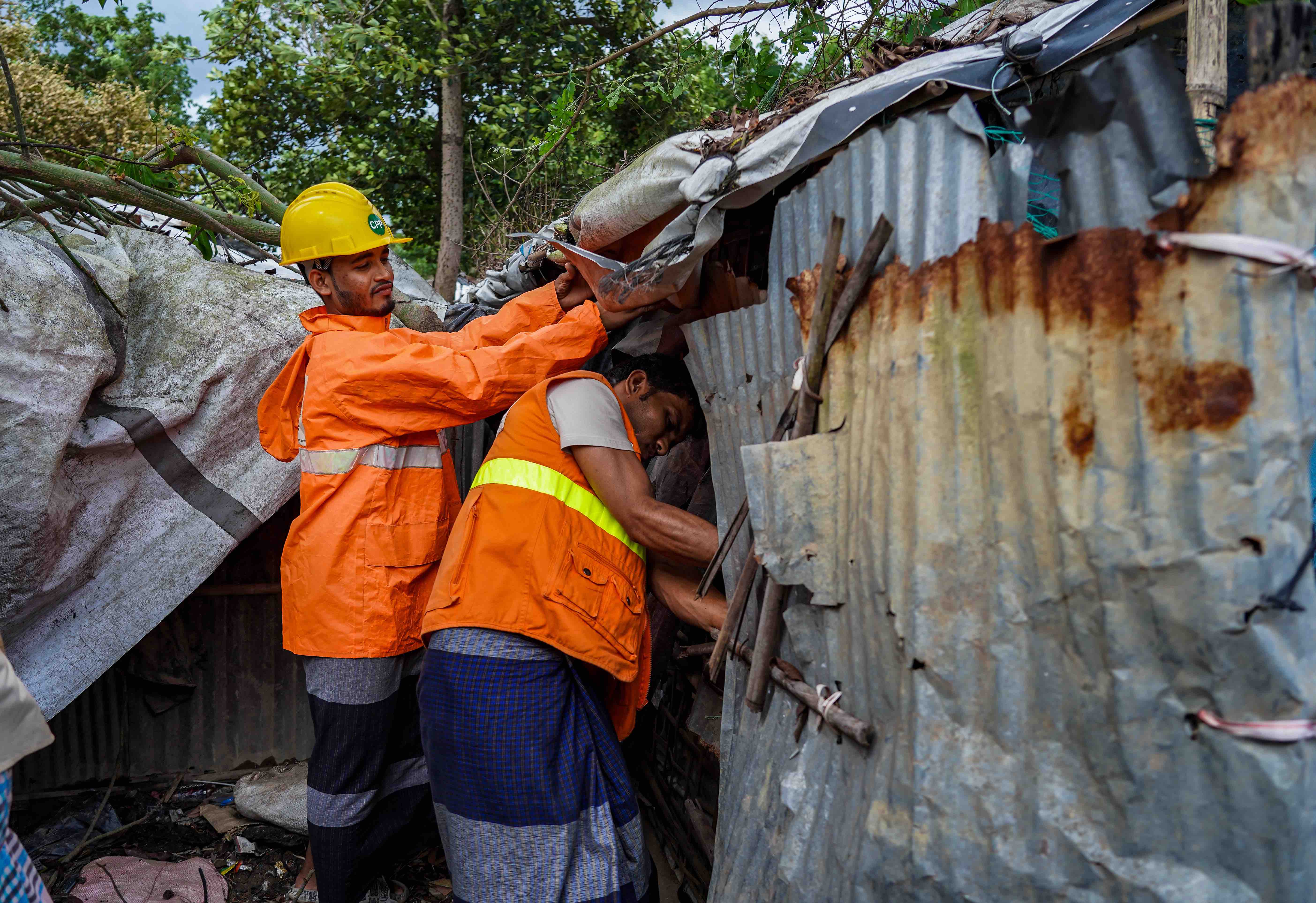 Two volunteers in the Cox's Bazar settlement in Bangladesh work to strengthen a shelter in Camp 26 before cyclone Mocha hit in 2023.