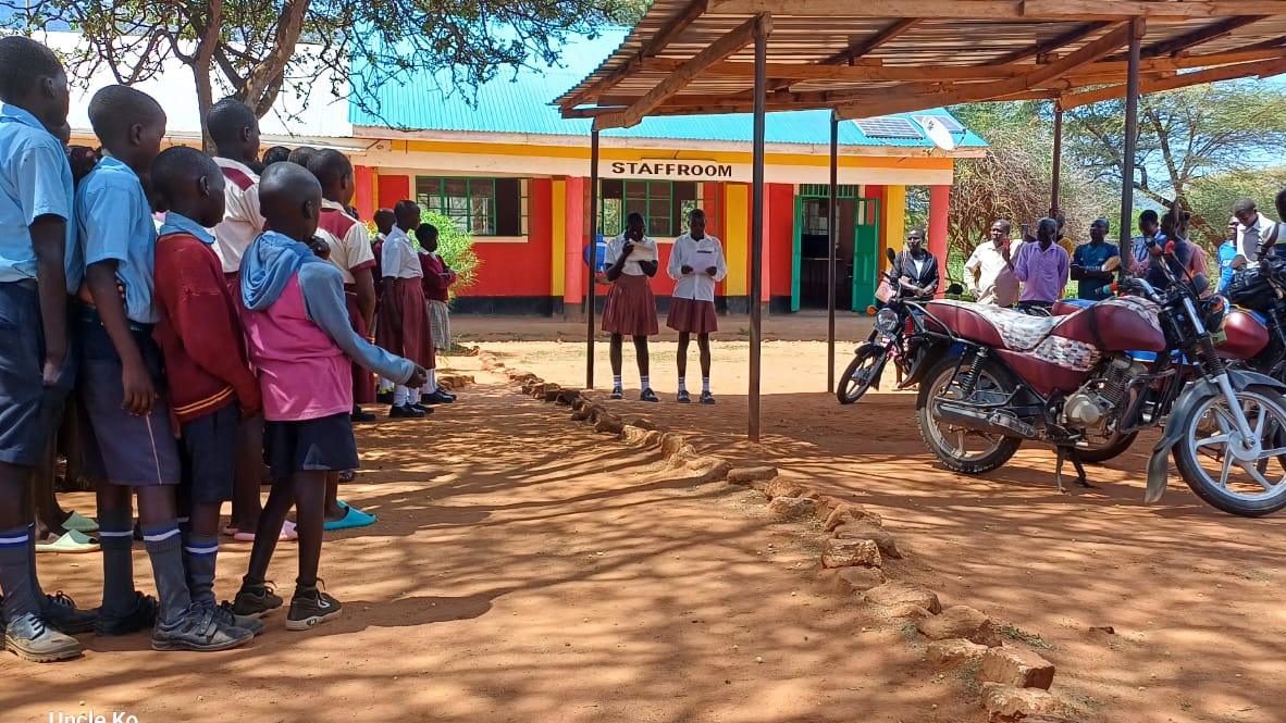 Two students in West Pokot perform a poem as part of their Chanuka Challenge event, watched on by teachers and fellow pupils.