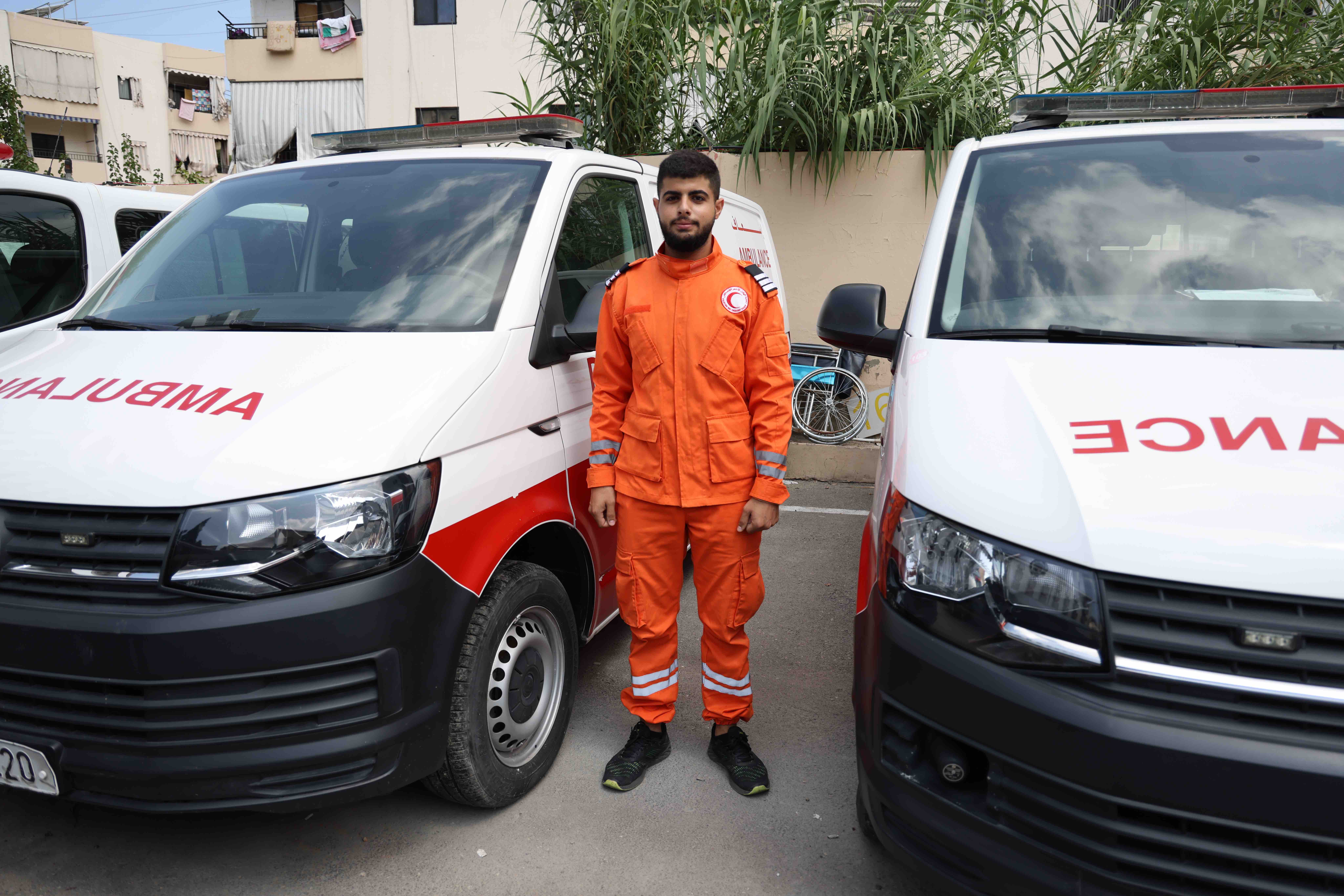 Proudly wearing his Palestine Red Crescent emergency medical services uniform, 19-year-old Ahmad Marwan El Issa stands in front of an ambulance, ready to respond at any time.