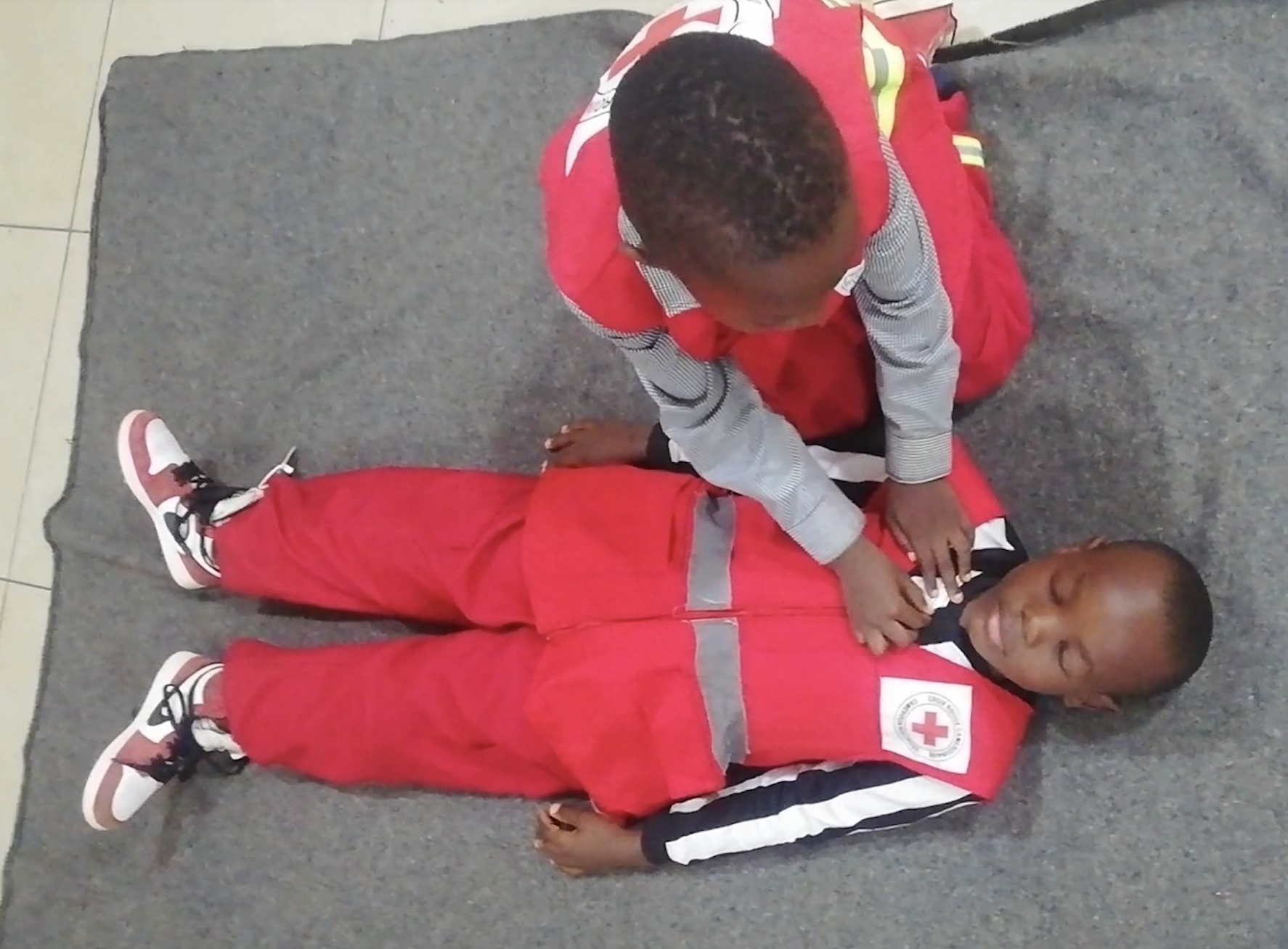 Two young children take part in a first-aid learning session organised by the Cameroon Red Cross.
