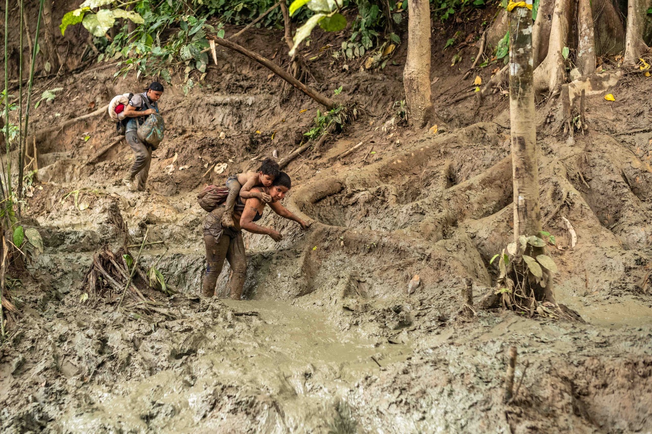 With each step, this woman carrying a child on her back, sinks deeper into the mud, and her struggle to complete the trek becomes increasingly daunting. 