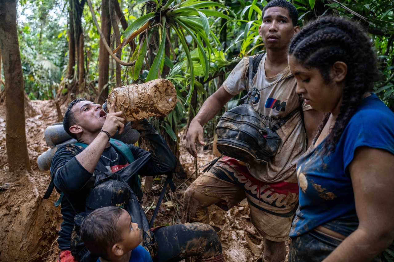 In this image taken in the heart of the jungle, a group of migrants share the last drops of water from a plastic gallon container. 