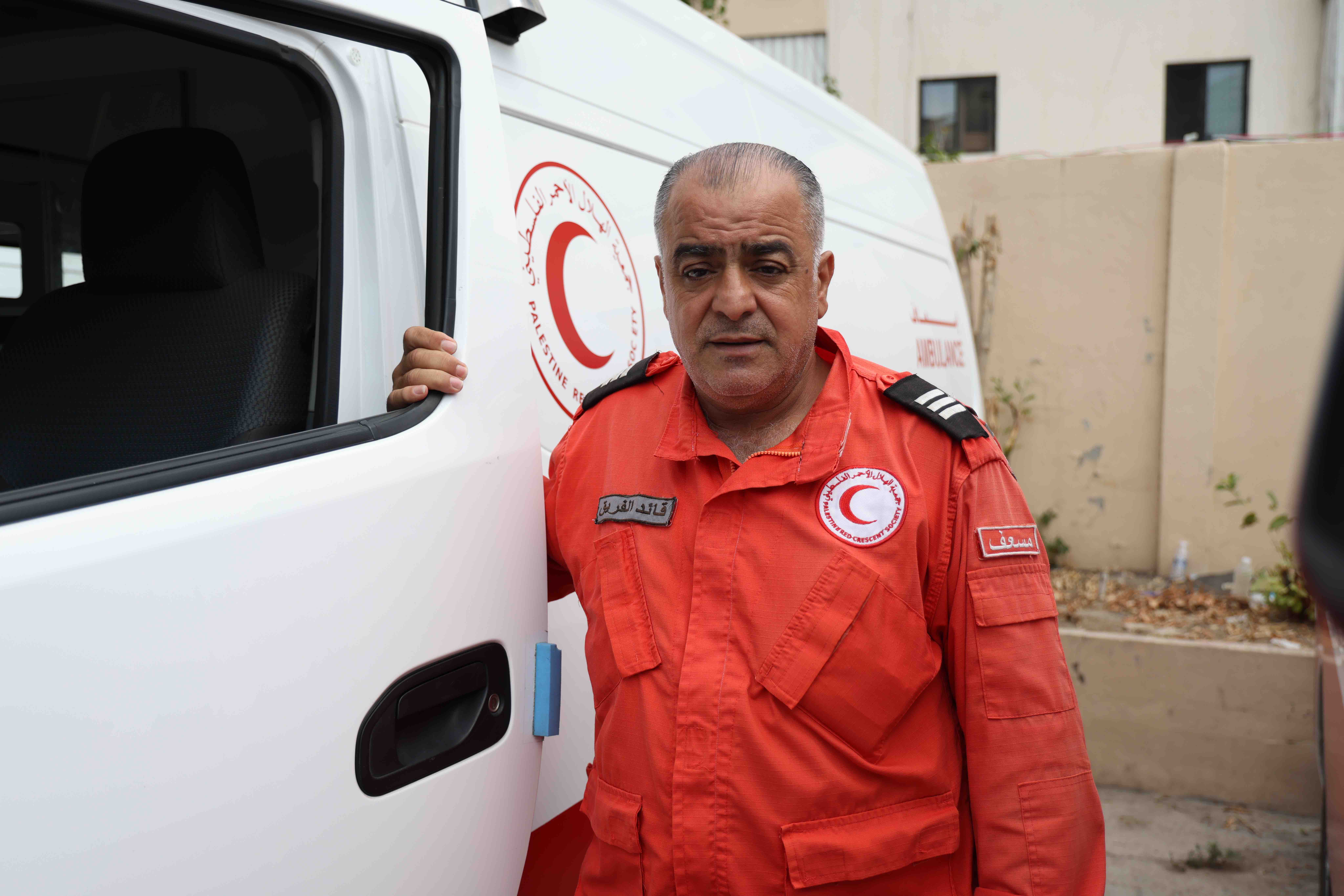 Hossam Sabha, a first responder who has been with the Palestine Red Crescent Society in Lebanon for almost 40 years, stands next to the ambulance he often drives.