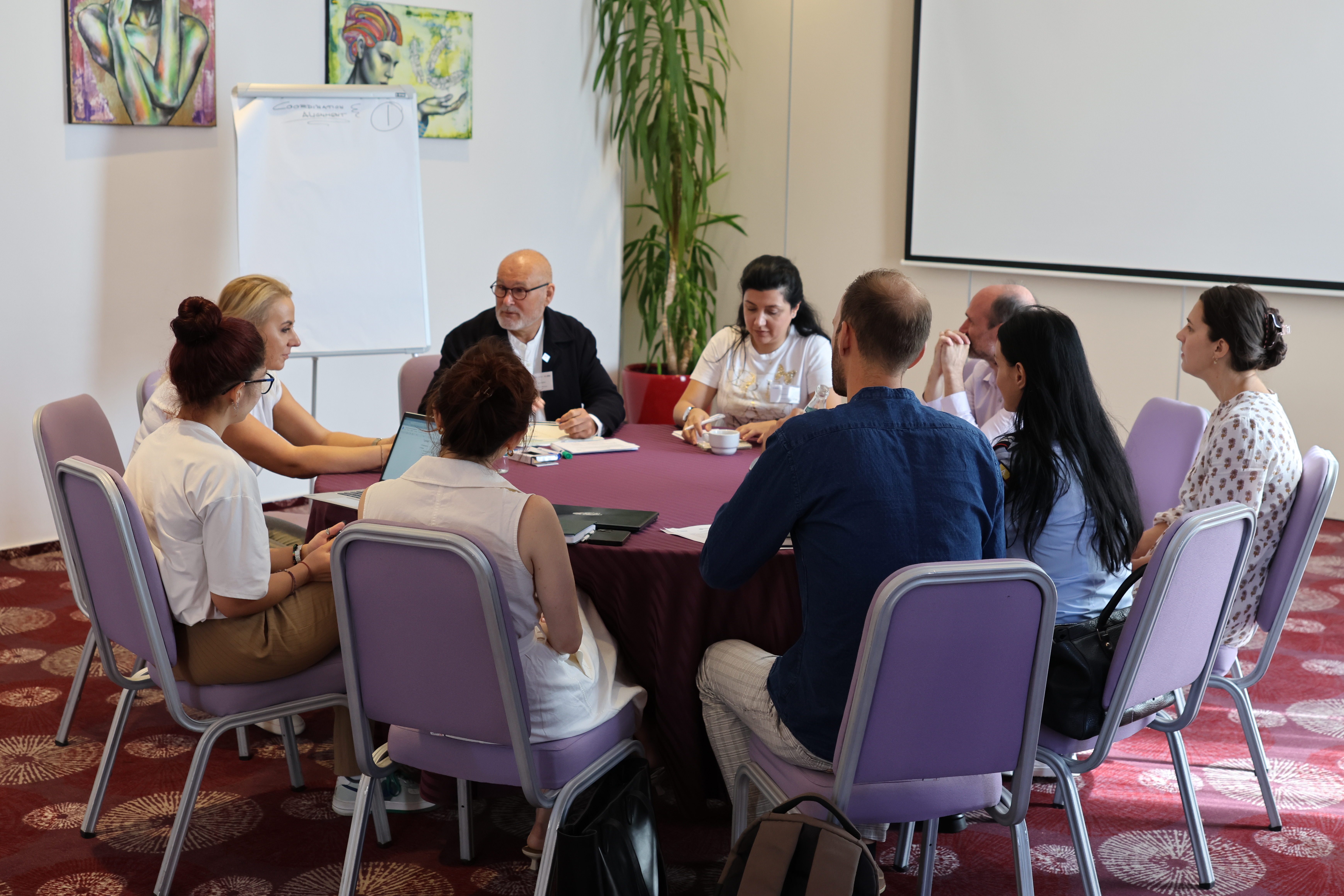 Representatives from the IFRC, the Romanian Red Cross and other partner humanitarian organizations gather around a table to share lessons learned and discuss results from cash-assistance programmes in Romania.