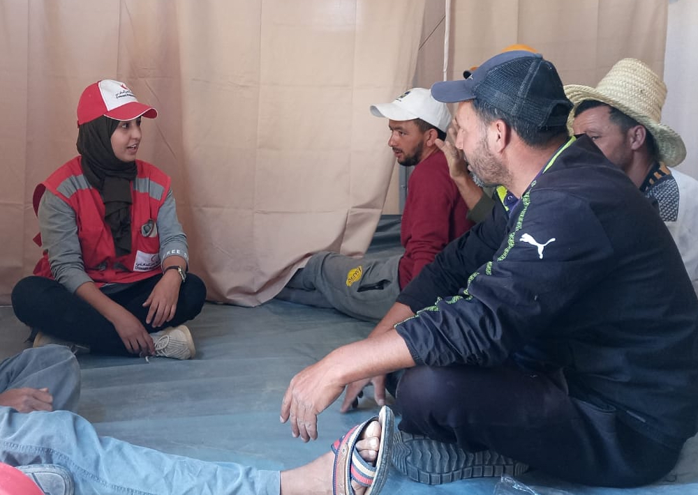 Moroccan Red Crescent shelter officer Naima sits down with community workers to train them on the process and techniques of installing temporary shelters.