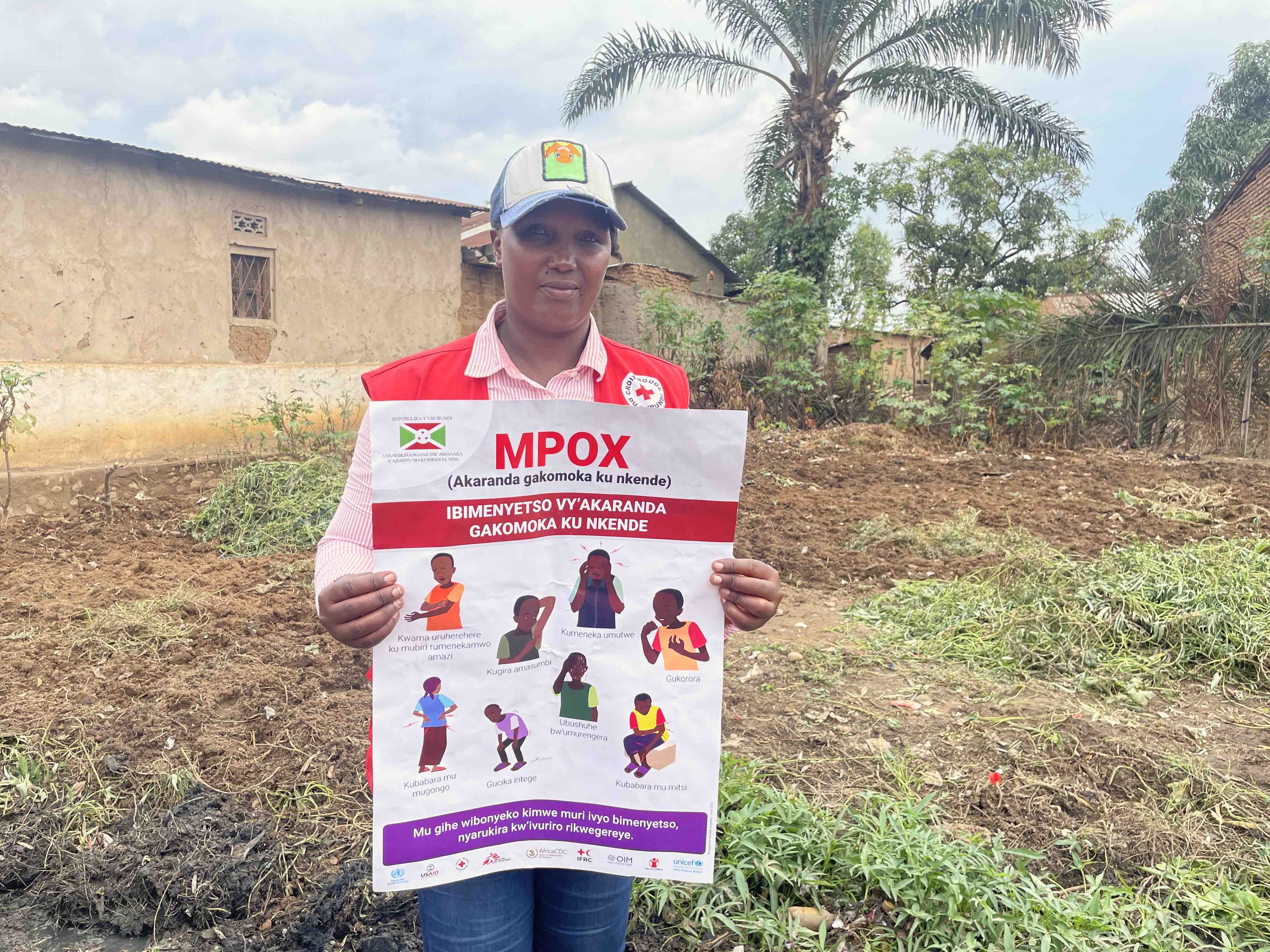 Burundi Red Cross volunteer Joselyn Ndayishimiye holds up an information poster about mpox prevention that she brings to local communities in her daily work against the spread of mpox. 