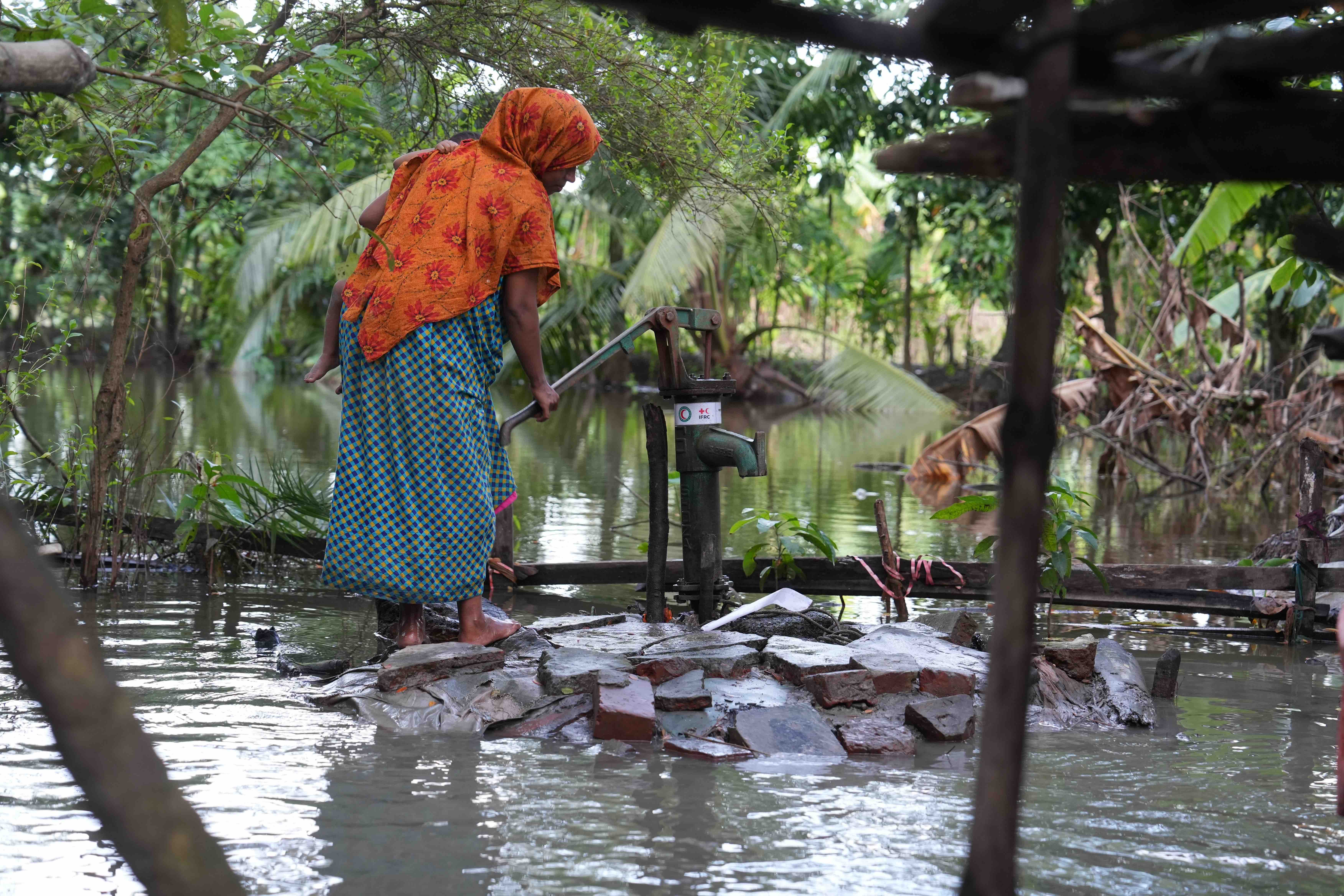 Even when surrounded by floodwaters, people often lack access to clean, drinkable water. This woman has waded to a water pump provided by the IFRC and the Bangladesh Red Crescent.