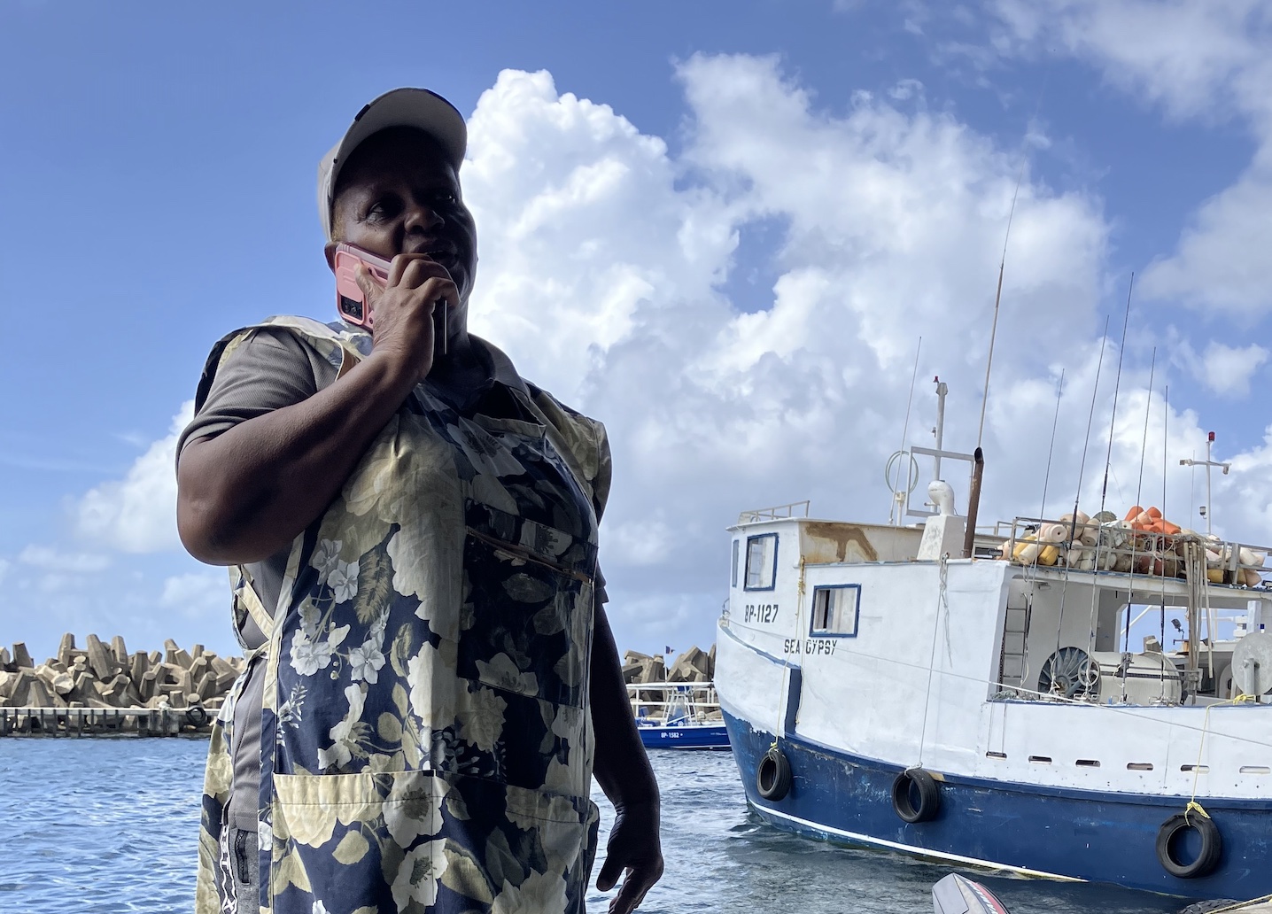 Fish vendor June Cummins stands on the pier near the Bridgetown Fish Market in Barbados. Four months after the storm, her favorite fishing board, the Sea Gypsy, is ready for the sea.