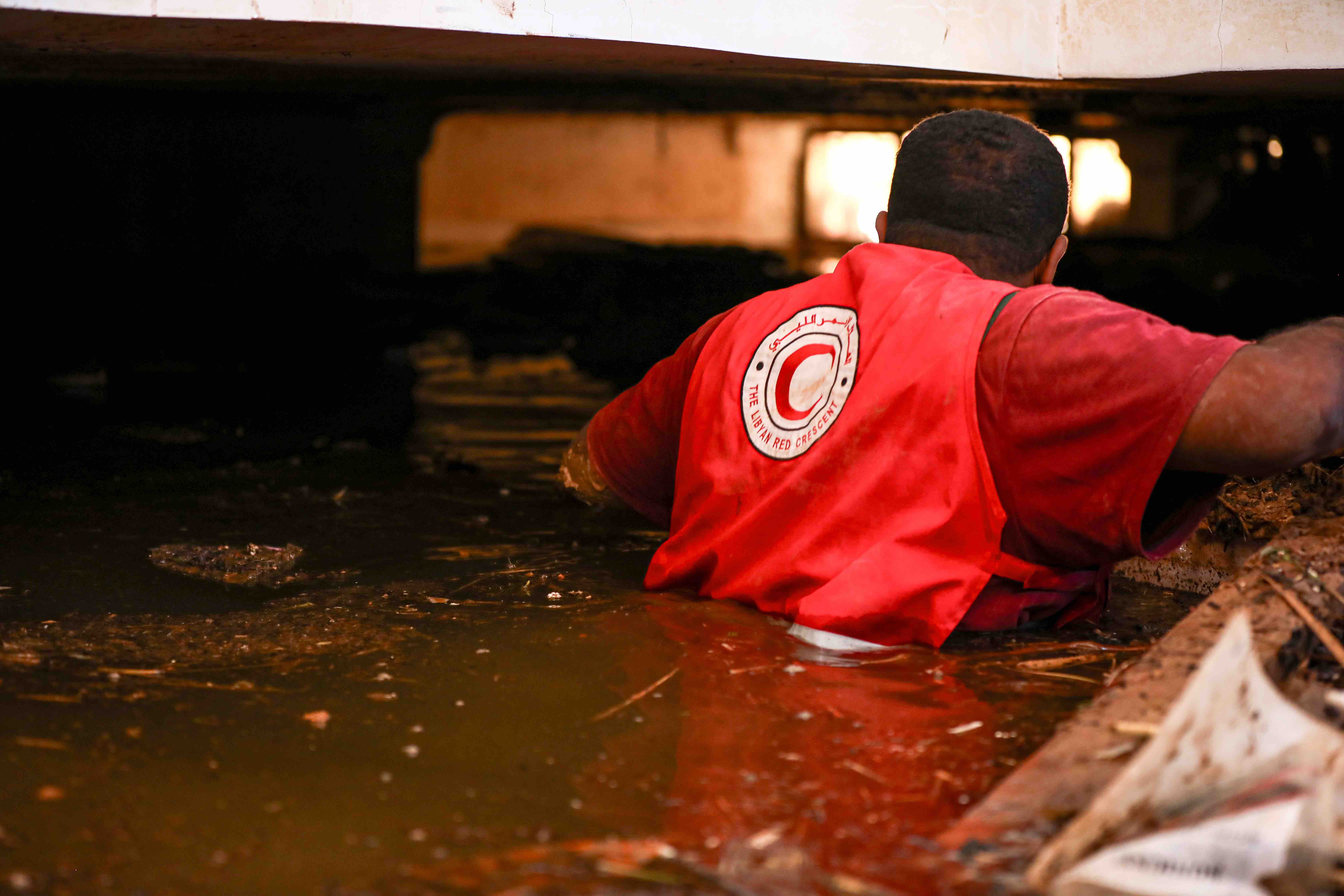 Libyan Red Crescent volunteer enters a flooded drainage in search of survivors.