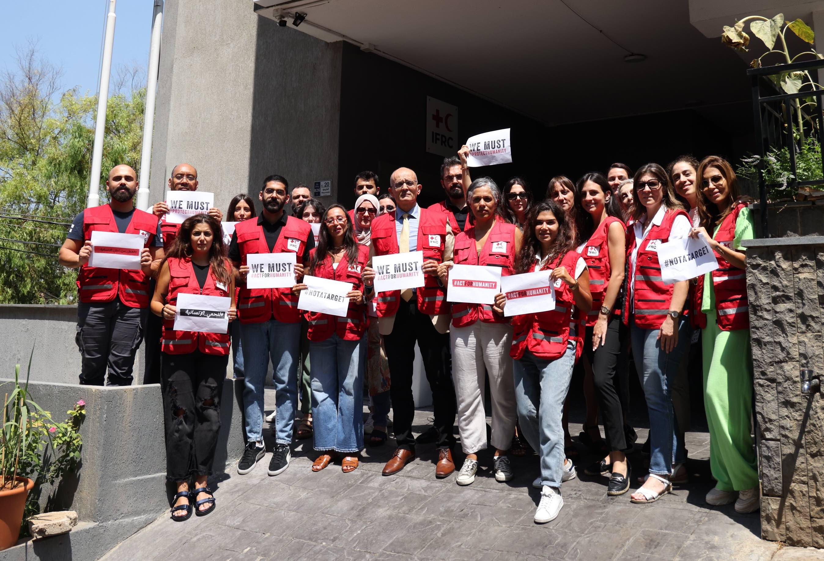 On World Humanitarian Day 2024, staff members at IFRC’s regional office for the Middle East and North Africa gather outside their headquarters in Beirut, Lebanon, holding signs that say ‘We are not a target’ and ‘We must protect humanity’ in response to the deaths of colleagues working in conflict and other emergency settings around the world.