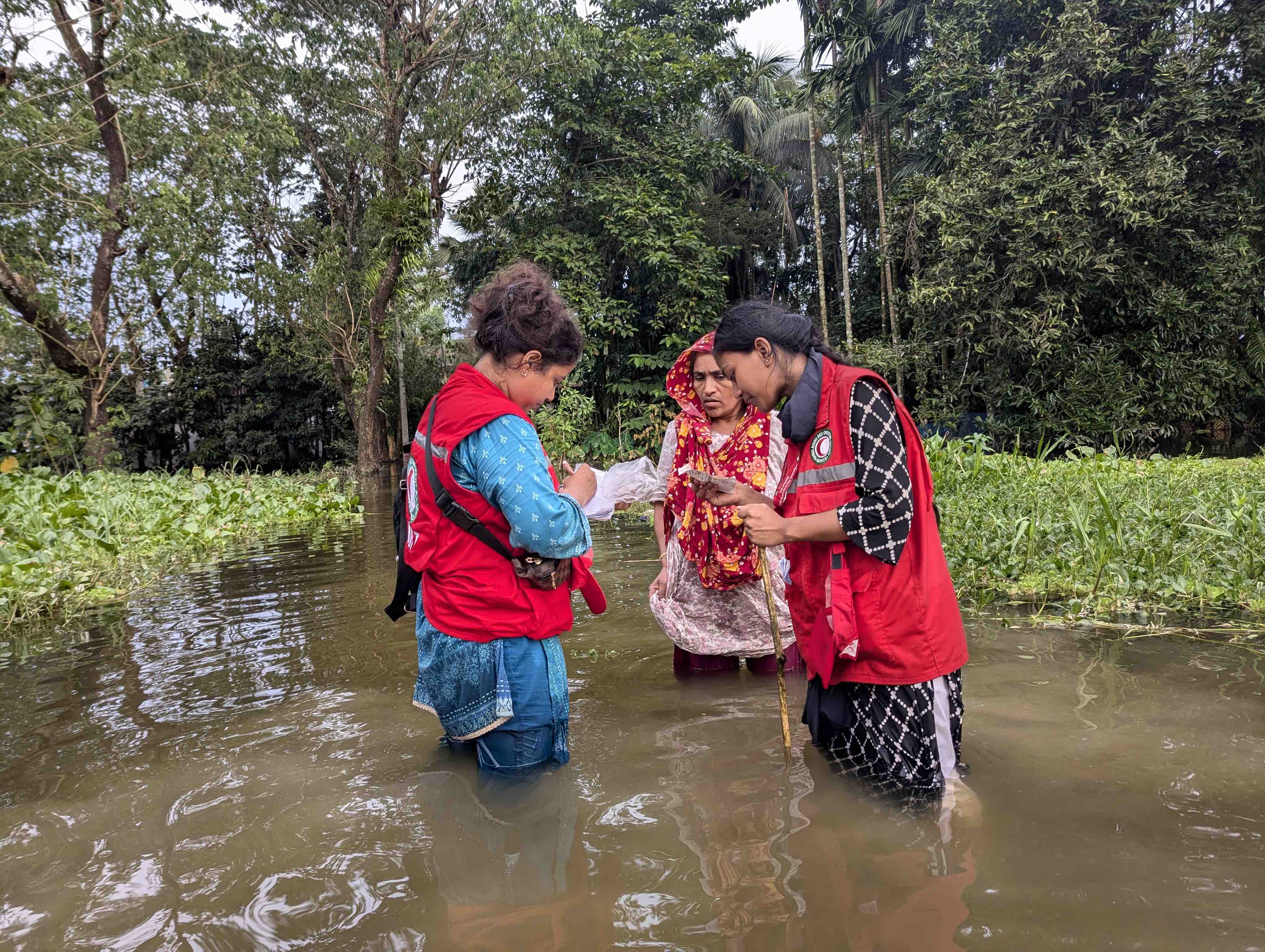 Red Crescent volunteers wade in waist-high waters to reach people, like the woman shown here, and assess their most urgent needs. 