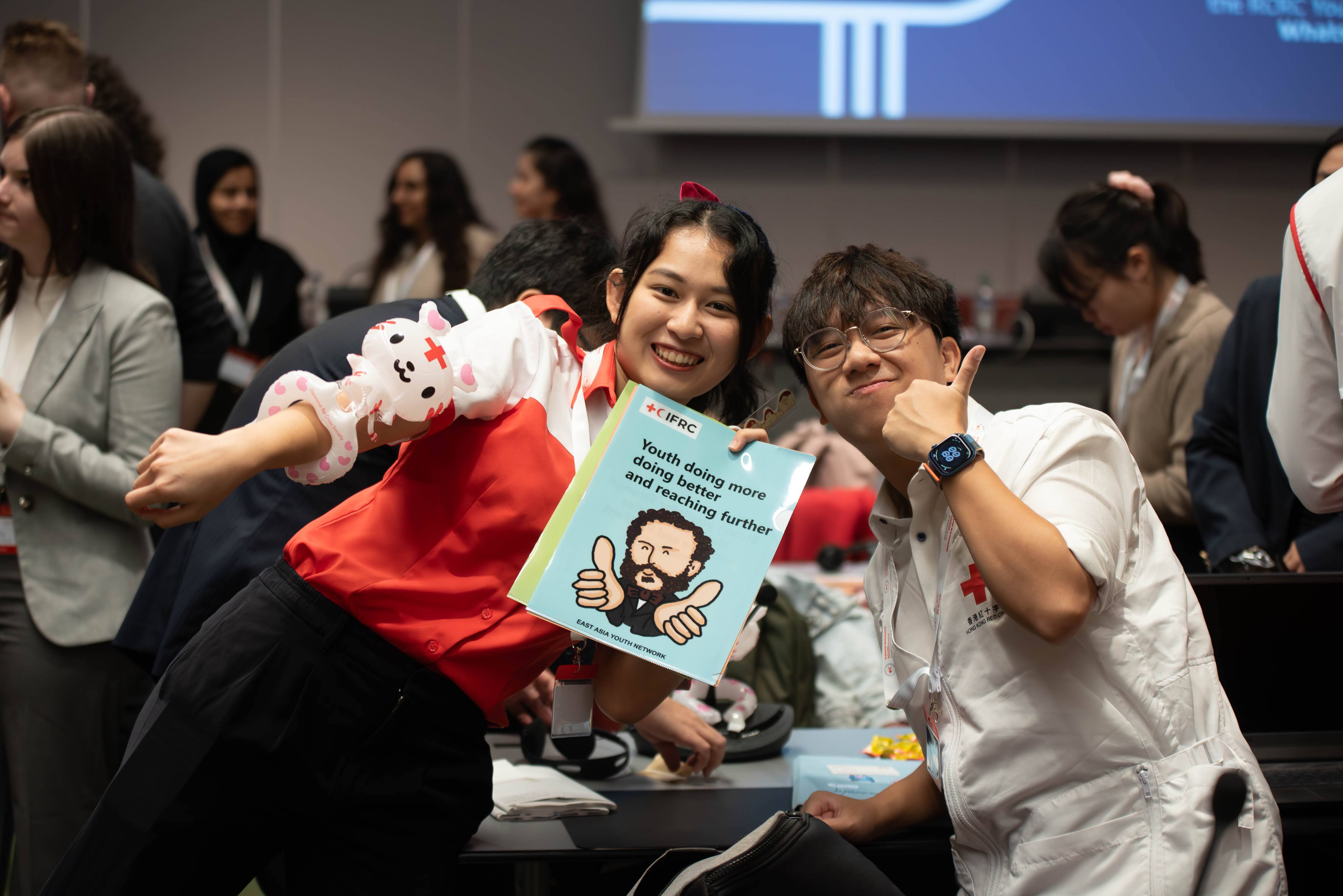 Volunteers attending the IFRC Youth Forum give a thumbs up as they hold up an IFRC document on youth participation.