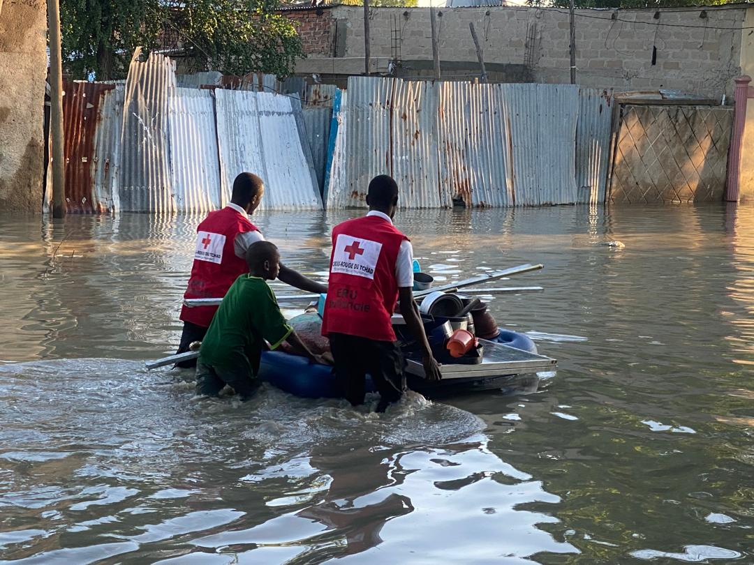 Volunteers with the Chad Red Cross help a young boy evacuate a flooded area safely.