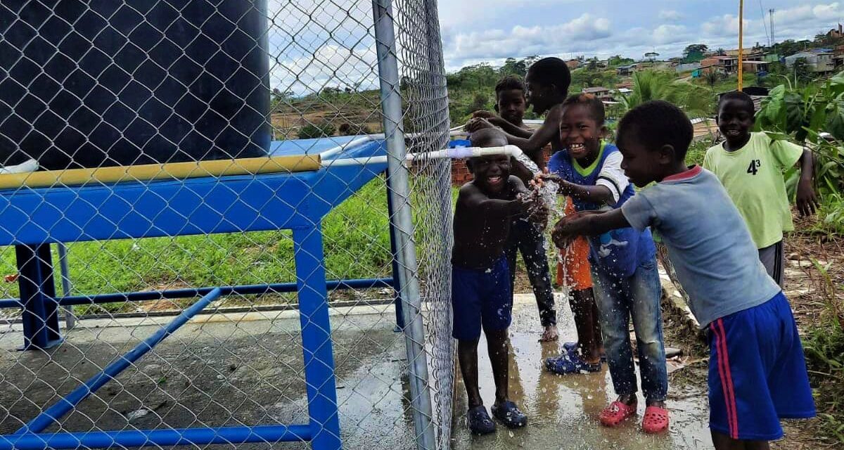 Children in Tumaco, Colombia wash their hands at a water point built by the Colombian Red Cross to provide clean water to underserved communities.