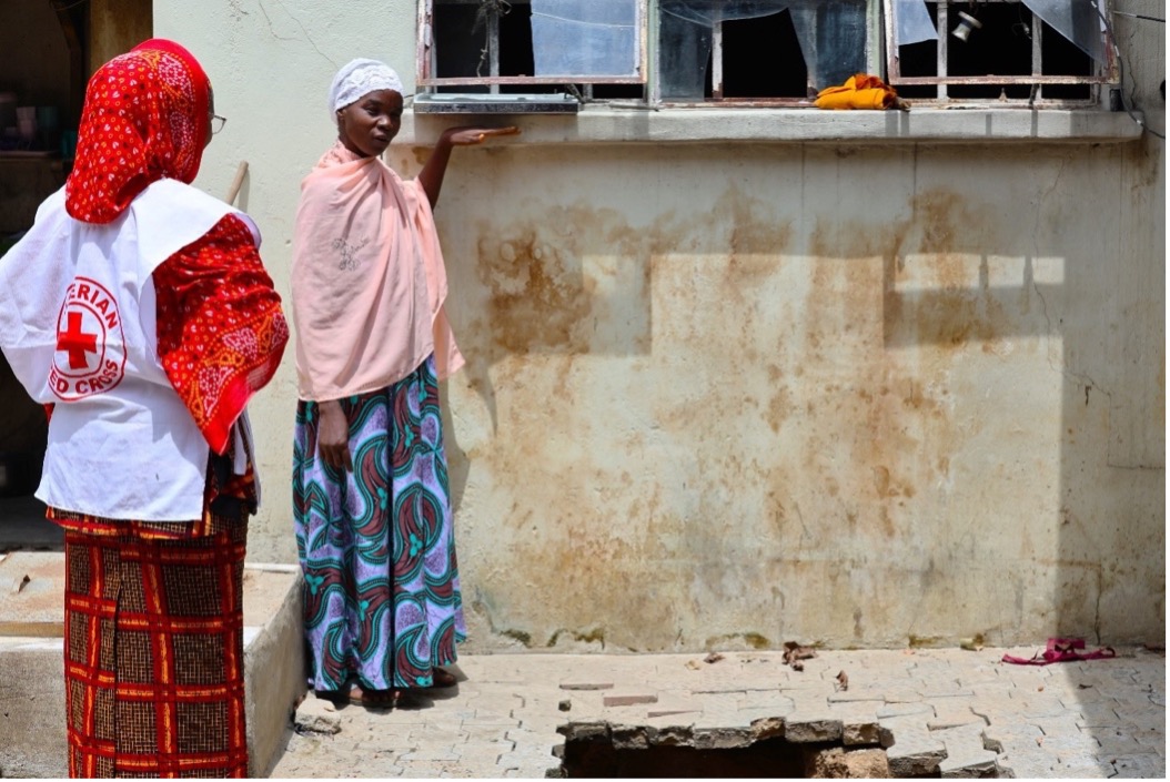 Standing in front of her house, mother-of-five Hadjara Habu places her hand on a window sill above her left shoulder to show the height the water reached during recent floods.