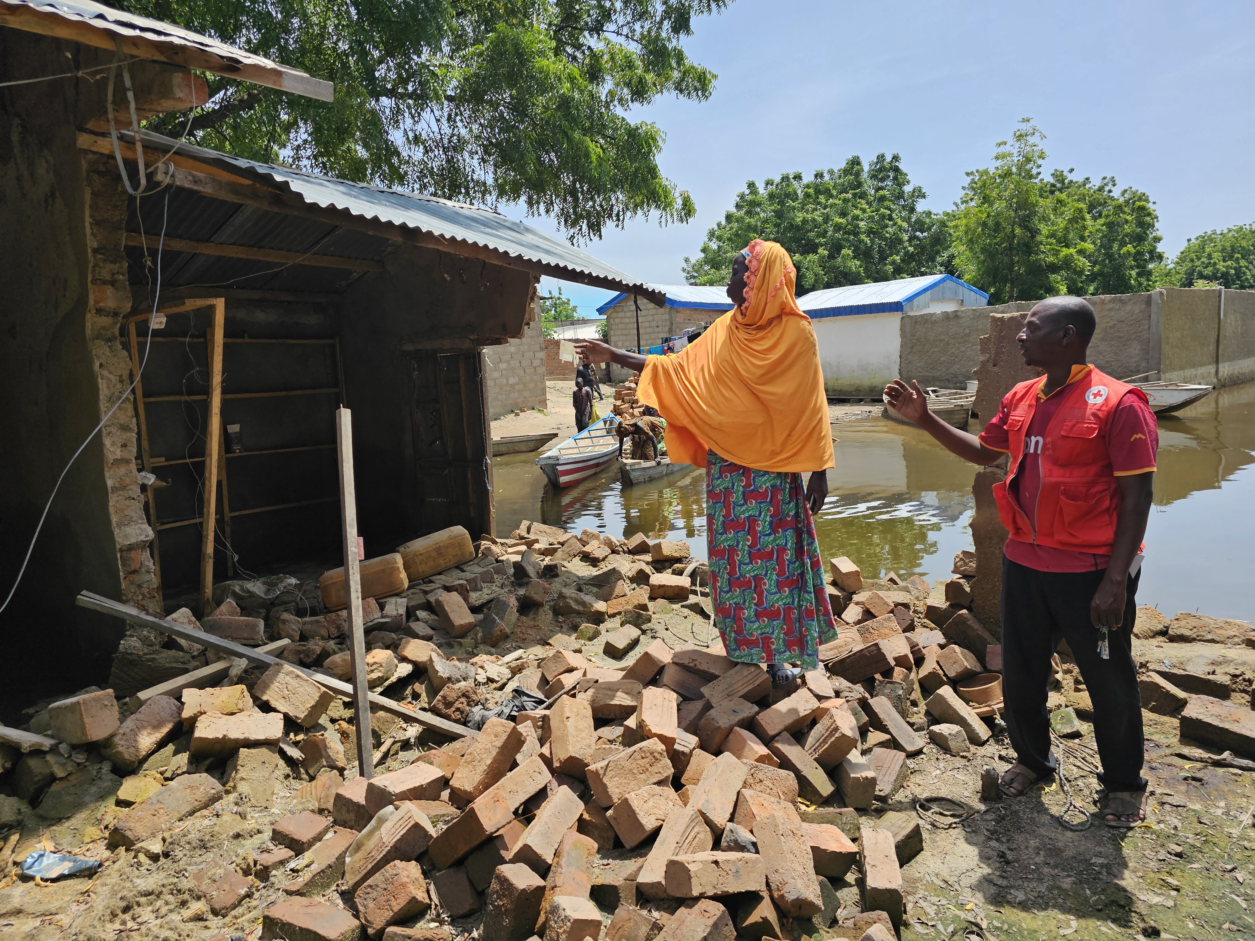 A woman shows a Cameroon Red Cross volunteer the damage caused by recent floods after heavy rains in Cameroon's Far-North region. More than 350,000 people are in need of immediate assistance with shelter, food and non-food items.