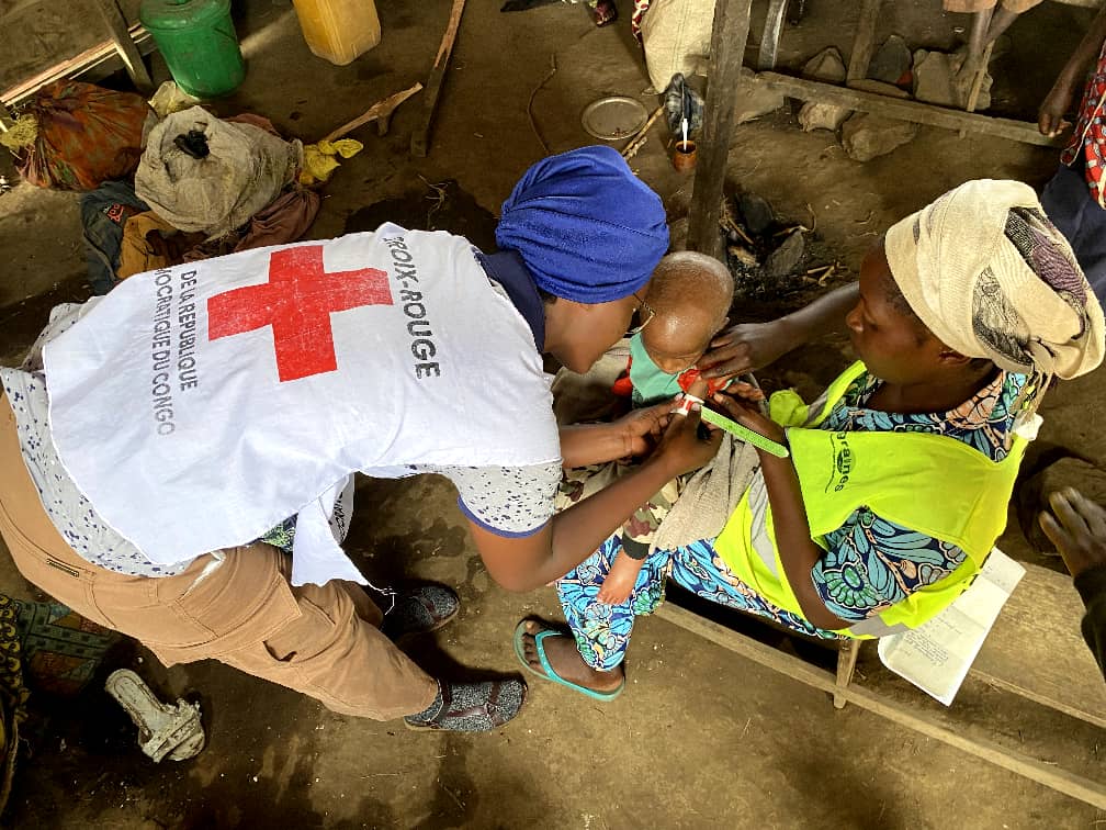 Volunteers from the Red Cross of the Democratic Republic of the Congo measure the upper arm of a small child as part of a nutritional screening being conducted in North Kivu, an area heavily impacted by food insecurity due to ongoing fighting.