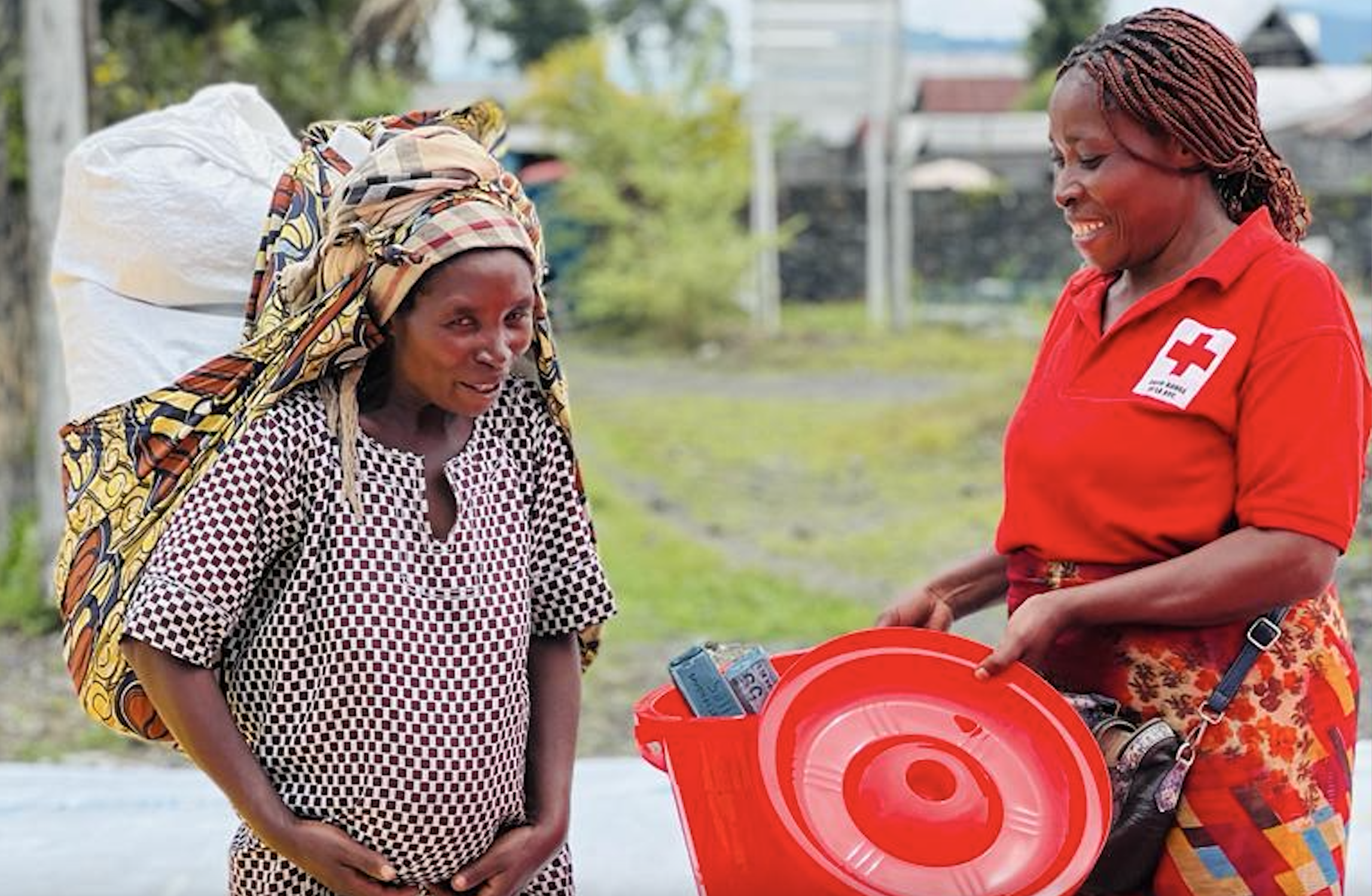 A volunteer for the Red Cross of the Democratic Republic of the Congo shares a smile and friendly word with a pregnant woman while offering hygiene information during an emergency rapid response in North Kivu province.