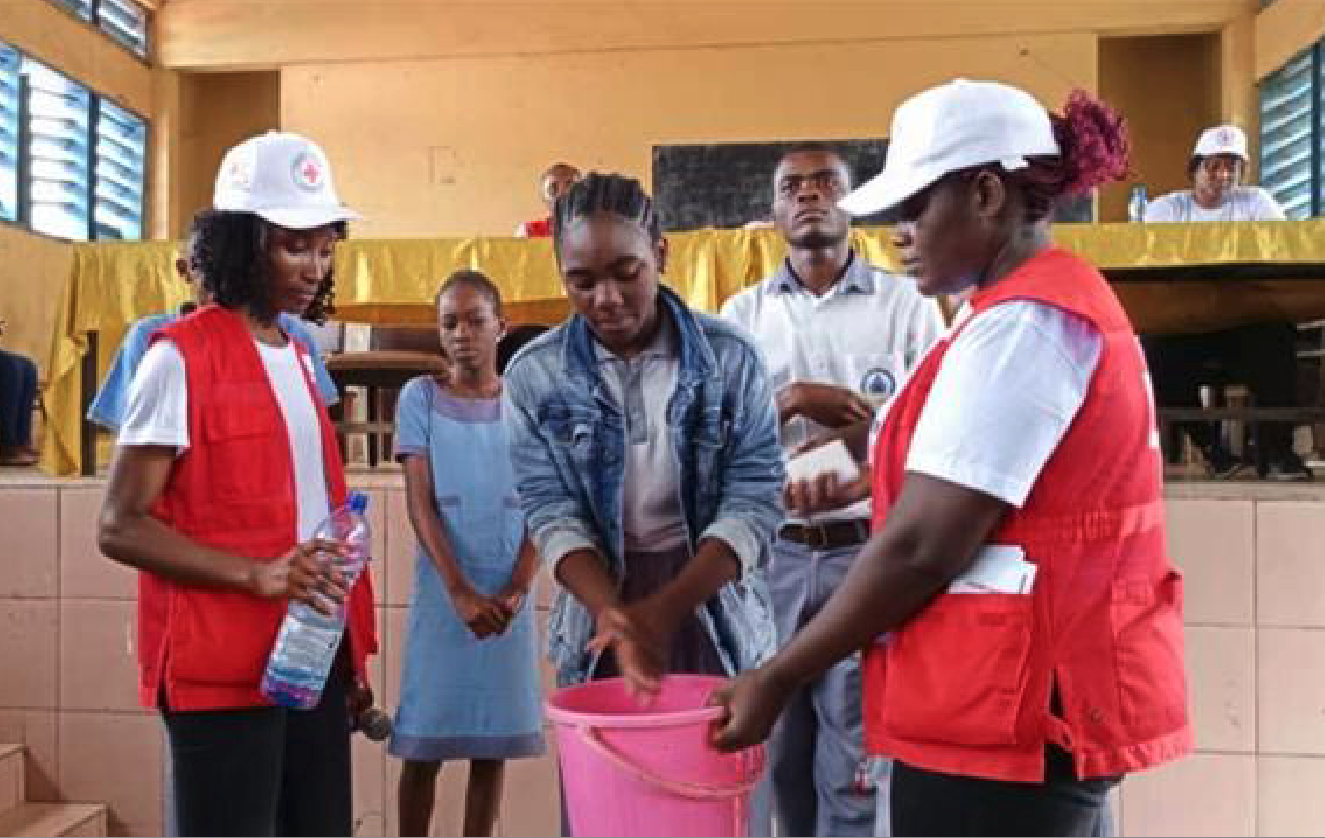 Architophel Ntsiakulu (left), a volunteer with the Gabon Red Cross Society, helps provide a hand-washing demonstration and services during an Mpox prevention session.