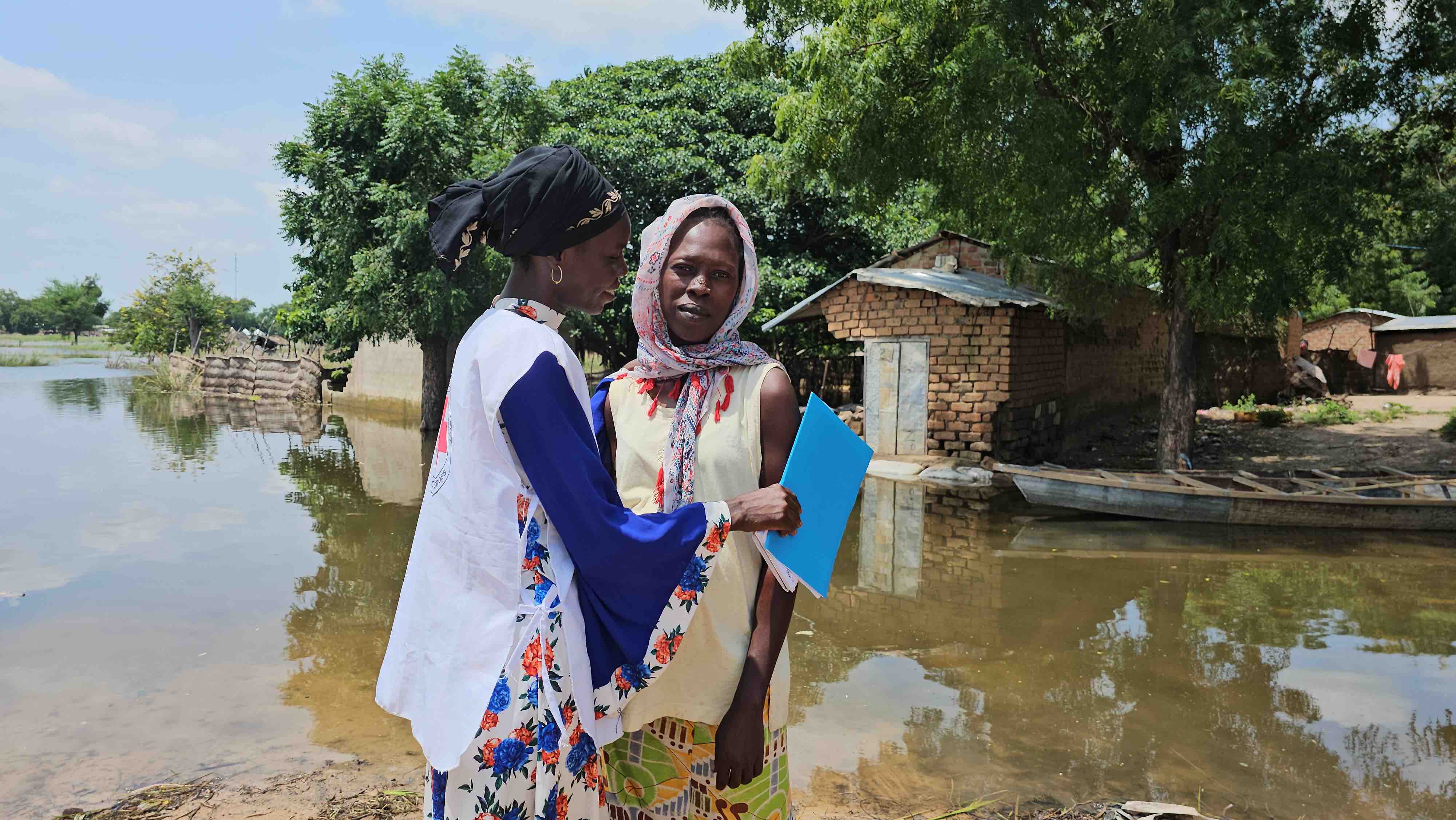 Cameroon Red Cross volunteer Adama Barka (left) comforts a pregnant mother who was forced to take a risky road to reach her flood-damaged house after floods submerged the main road to her home. 