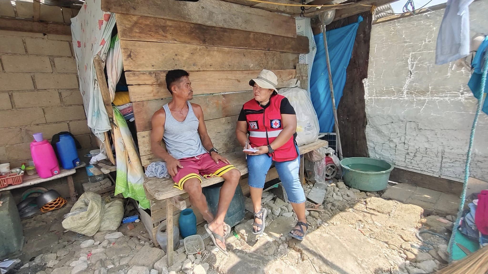 Felisa Buquel, a volunteer from the Isabela chapter of the Philippine Red Cross Society, talks to a man impacted by recent storms as part of damage assessments she does as a volunteer deployed to disaster areas. 